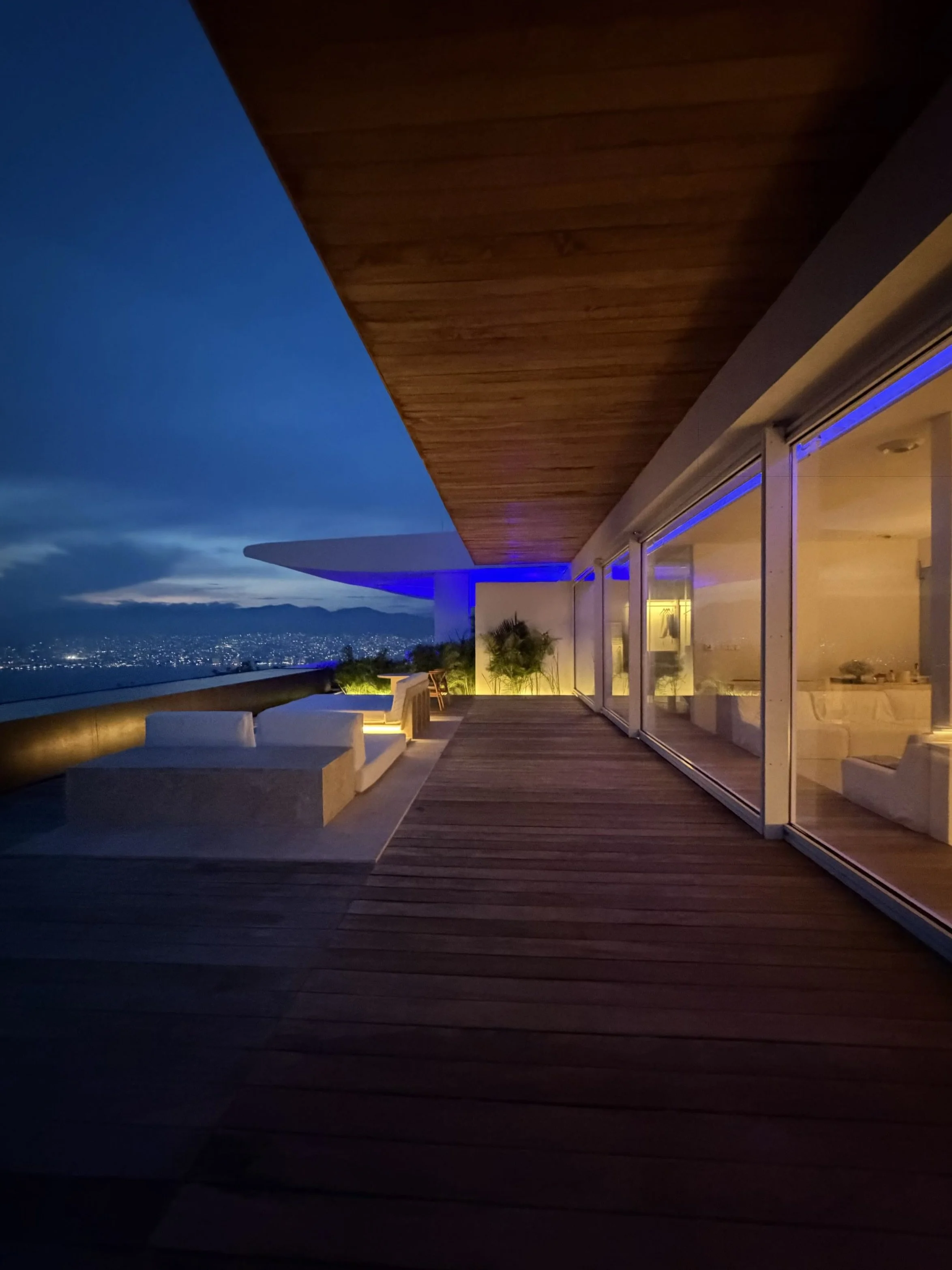 Signature Suite de Hotel Encanto. Terraza y habitación con vista nocturna en tonos cálidos y azules. 