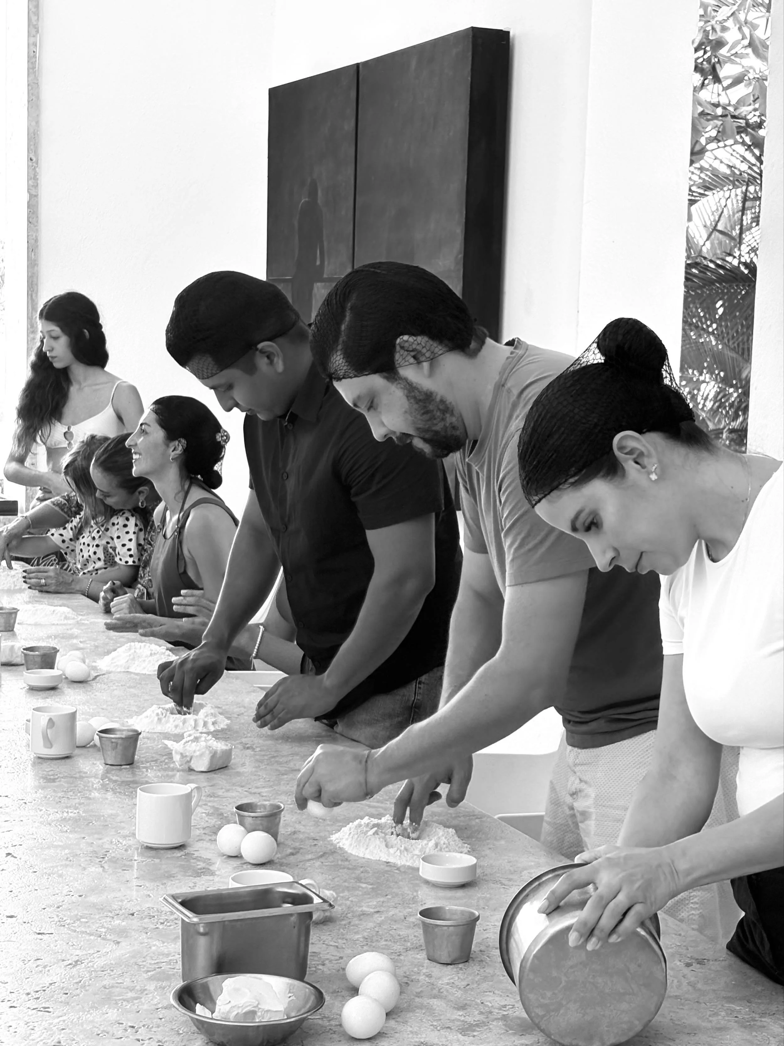 Taller gastronómico compartido en el Hotel Encanto Acapulco. Huéspedes habitando el espacio culinario de forma pausada.
