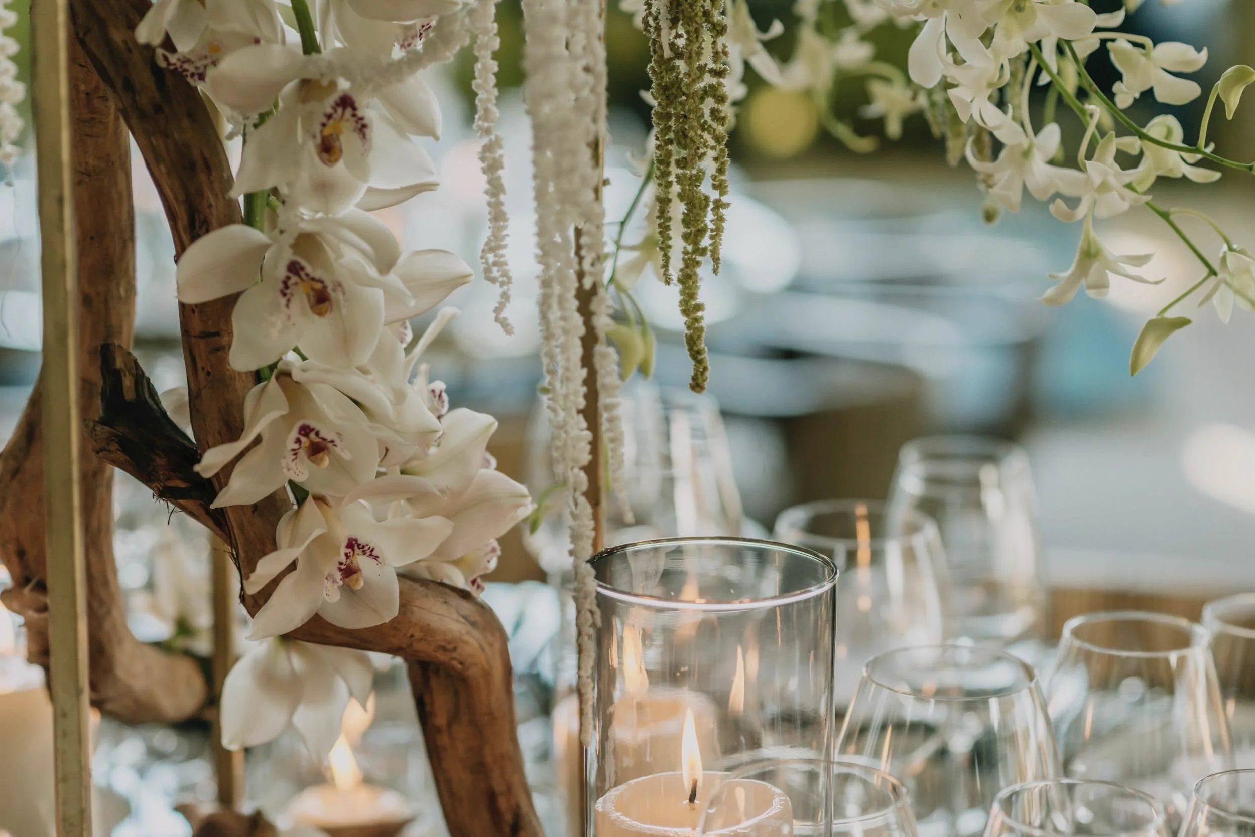 Orquídeas y velas reflejadas en cristal durante boda en Hotel Encanto Acapulco. Atmósfera íntima bajo la calma nocturna
