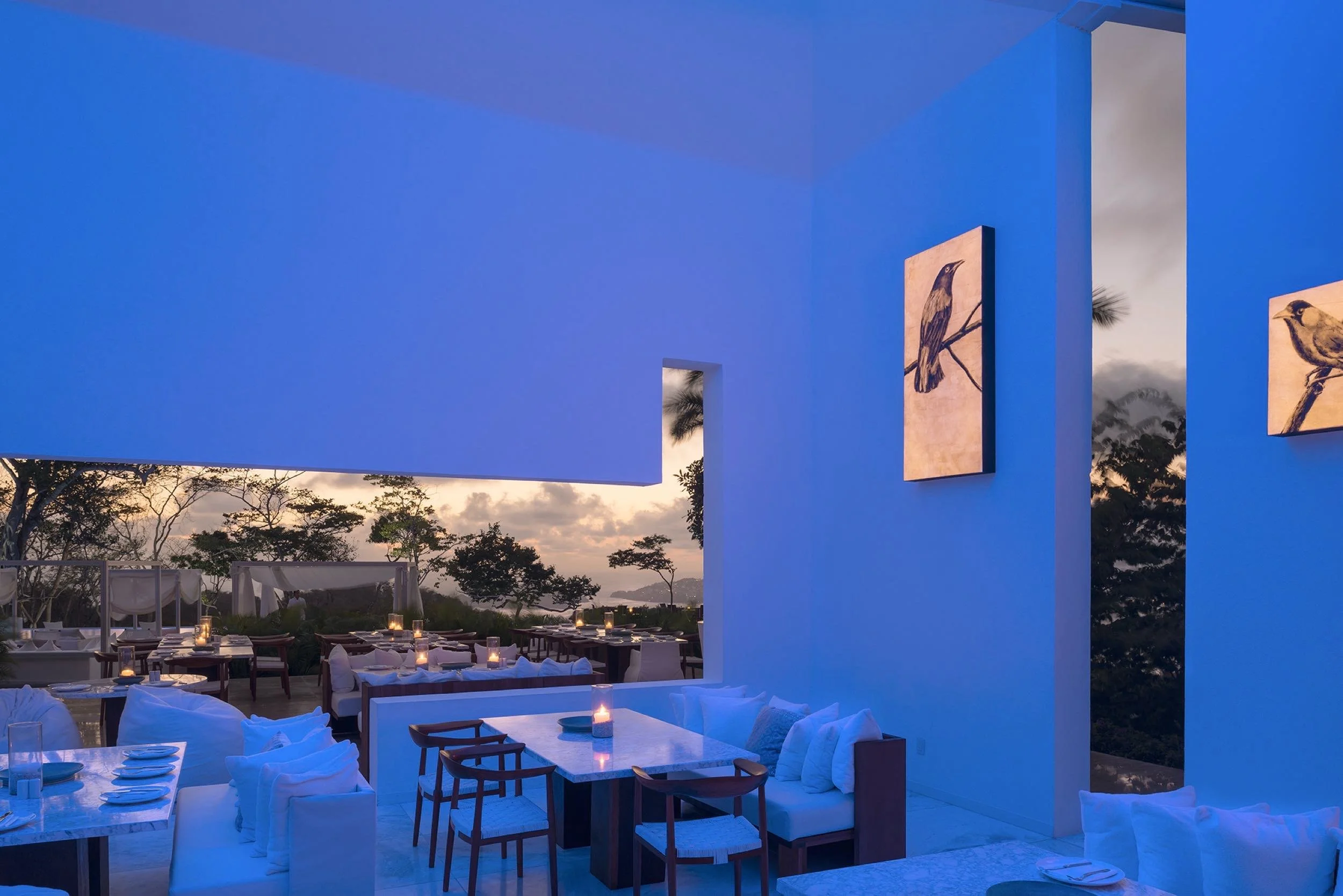 Restaurante Origen en Encanto Acapulco, con iluminación azul al interior y vistas a la bahía de fondo.