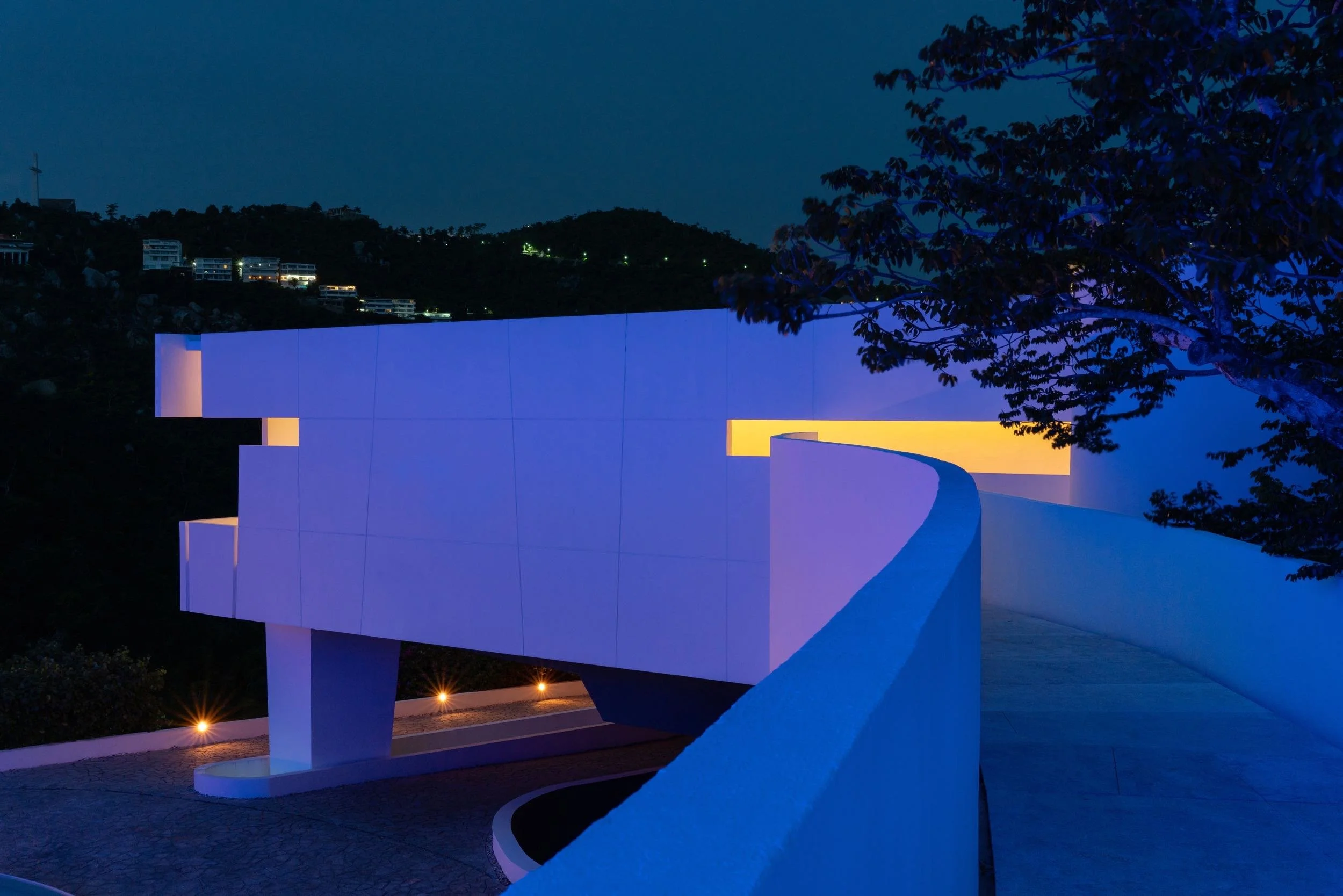Puente que lleva hacia un  juego  de luces y sombras nocturnas en la arquitectura de Taller Aragones en Encanto Acapulco. 