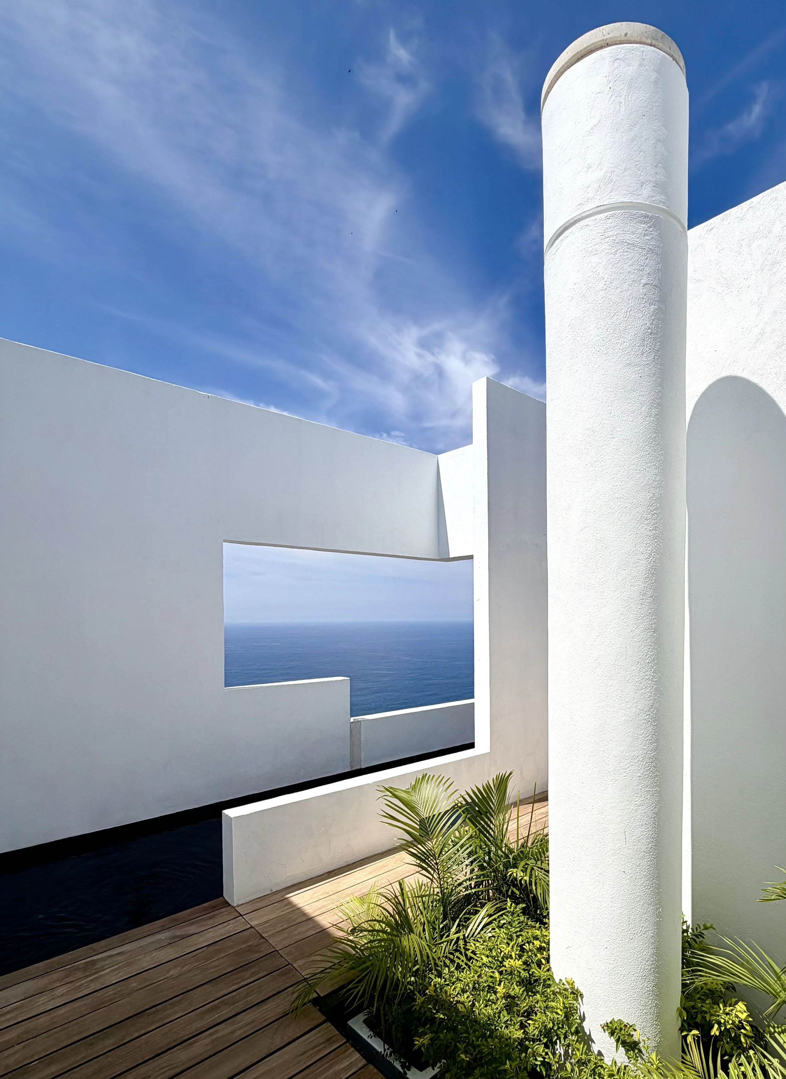 Ventana de habitación Signature Suite en Hotel Encanto. Arquitectura y Vegetación tropical con cielo azul y mar de cortes como remate visual.