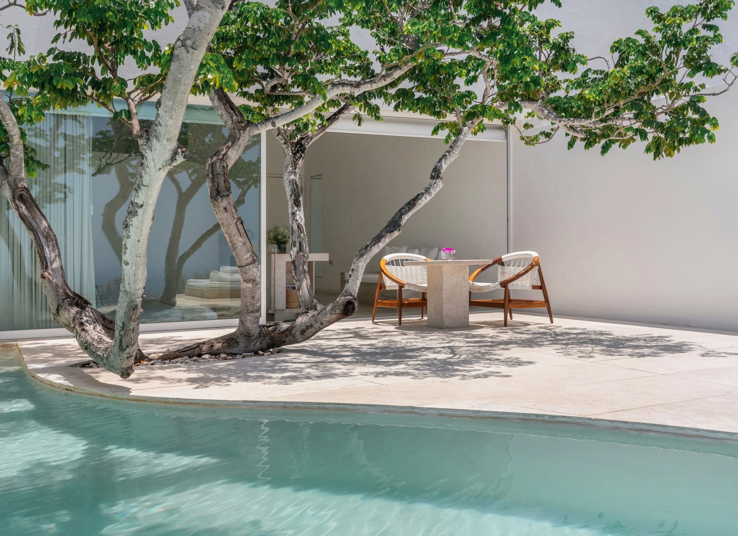 Mobiliario de madera y espacio de estar al aire libre en Ocean Pool Villa de Hotel Encanto. Escala humana integrada a la naturaleza local.