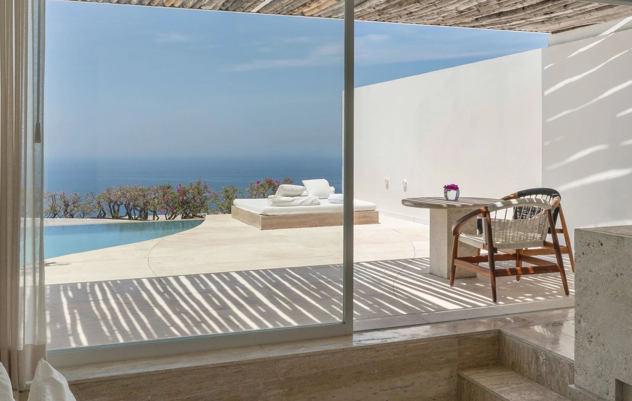 Asoleadero minimalista sobre concreto blanco en Ocean Pool Villa de Hotel Encanto. Geometría limpia en Brisas Marqués.