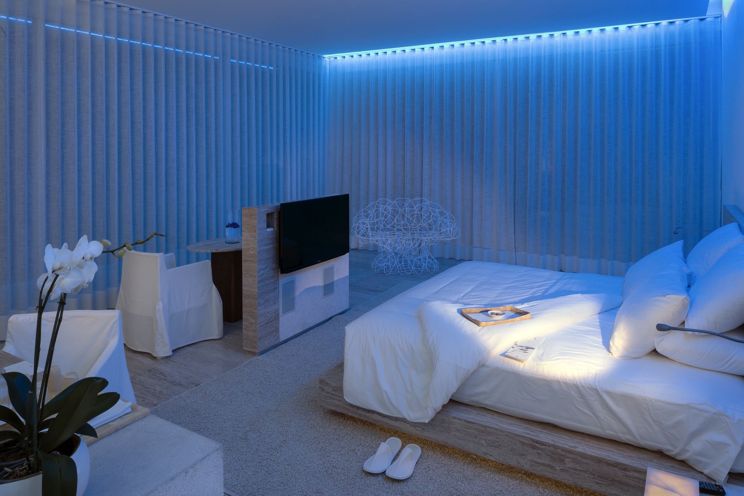 Atmósfera nocturna con luz azul en Ocean Designer Suite de Hotel Encanto Acapulco. Obra cromática de Taller Aragonés.