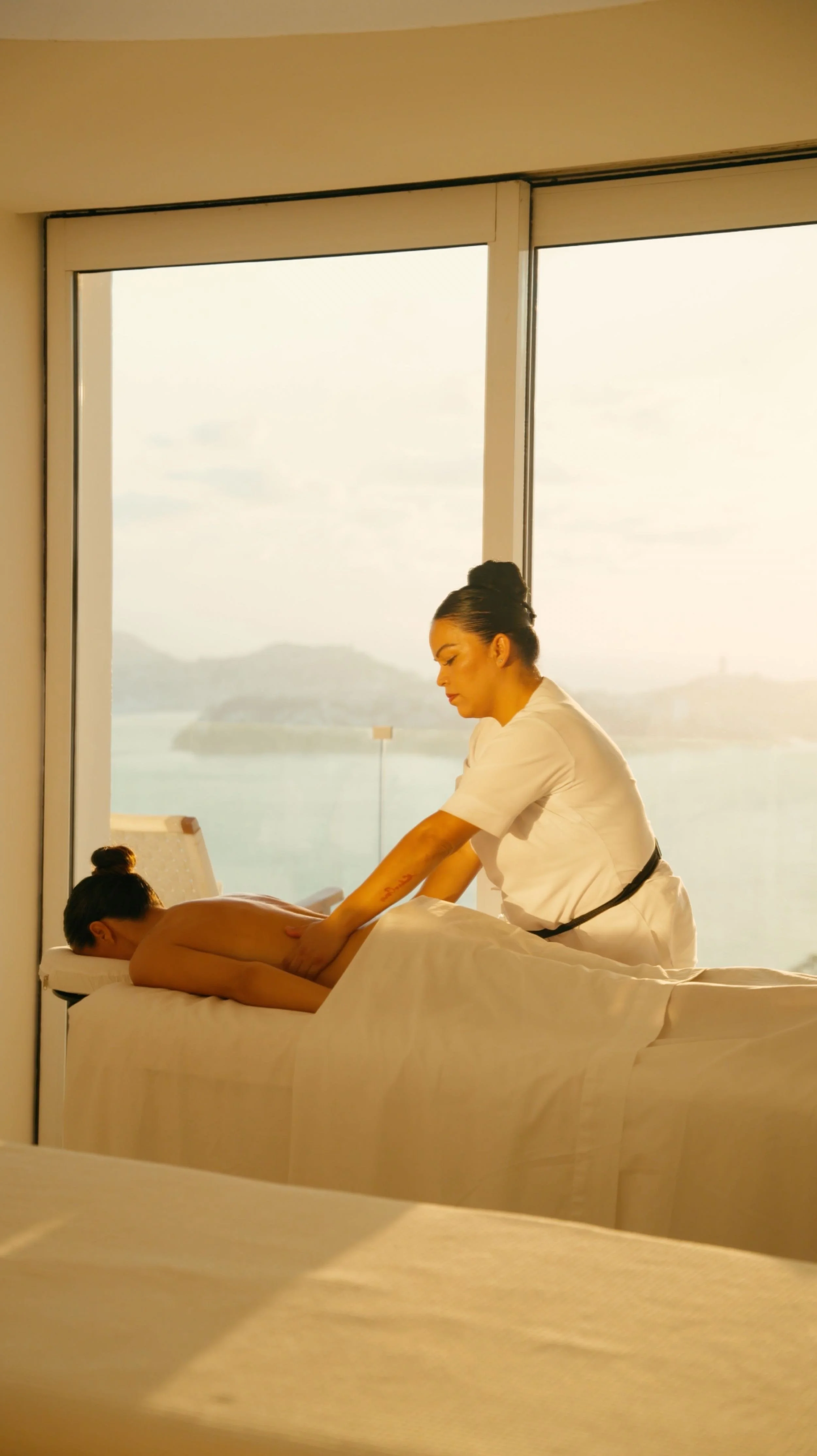 Masaje terapéutico frente al ventanal con vista al Pacífico en Hotel Encanto Acapulco. Espacio de sintonía espiritual."