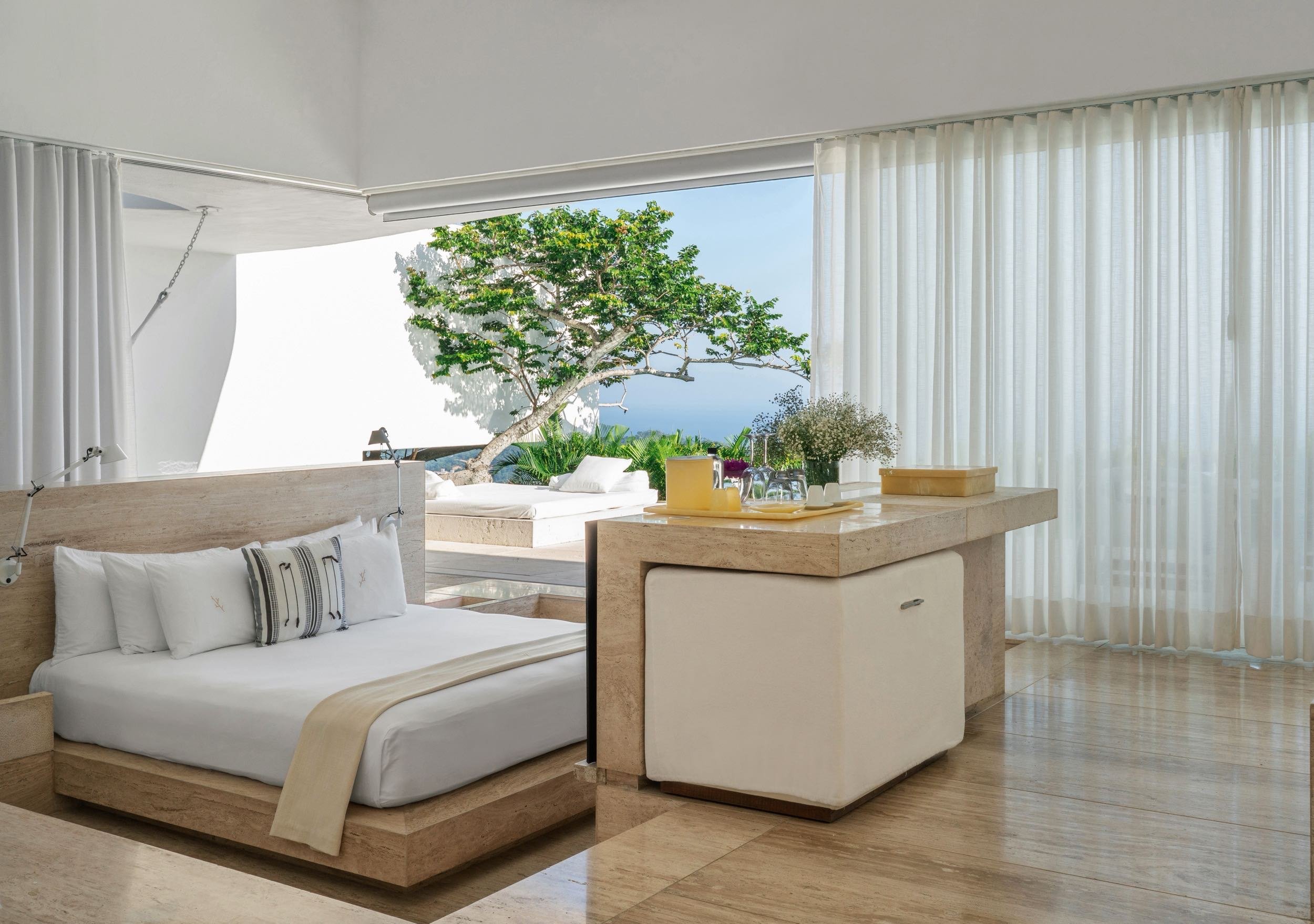 Arquitectura con calidez a traves de materiales suaves en Ocean Encanto Villa en Hotel Encanto Acapulco. Espacio abierto a escala humana con árbol y oceano al fondo