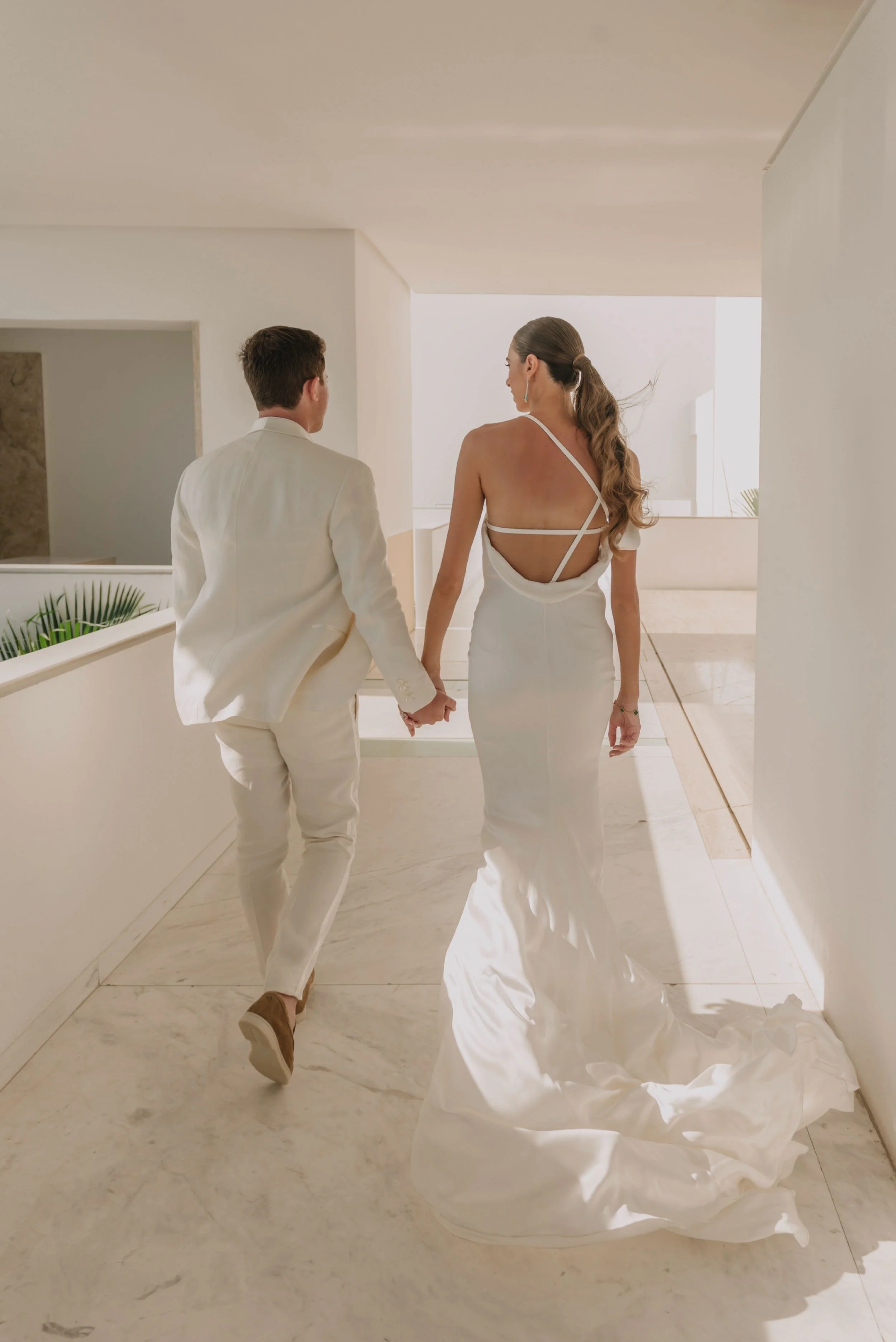 Novios en el pasillo blanco de Hotel Encanto Acapulco por Miguel Ángel Aragonés. Arquitectura a escala humana en bodas.