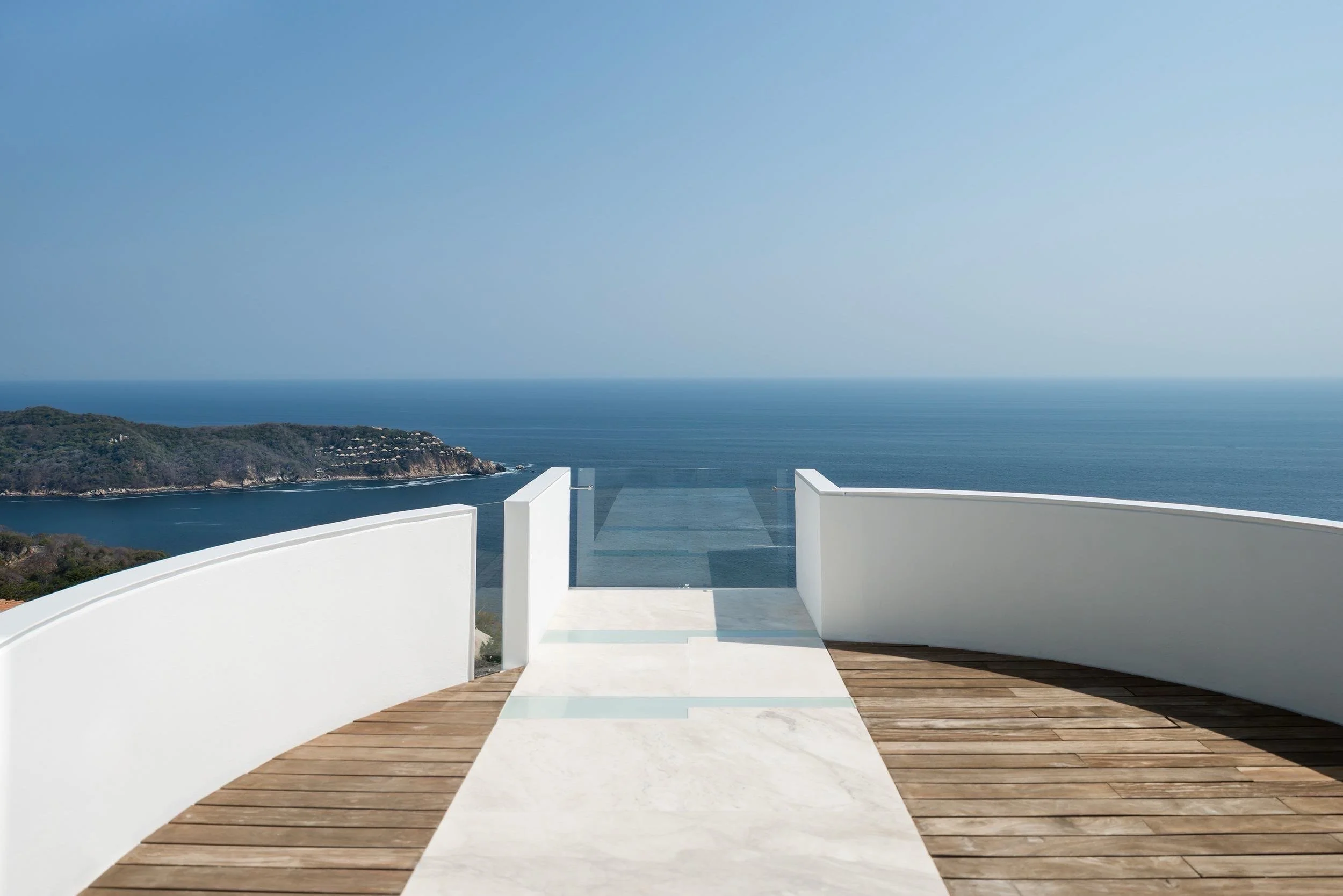 Terraza exclusiva con vista panorámica al mar Pacífico en el resort boutique Encanto Acapulco. Fotografía de Nicola Lorusso. piso de madera y mármol travertino con el mar de Acapulco de fondo. 