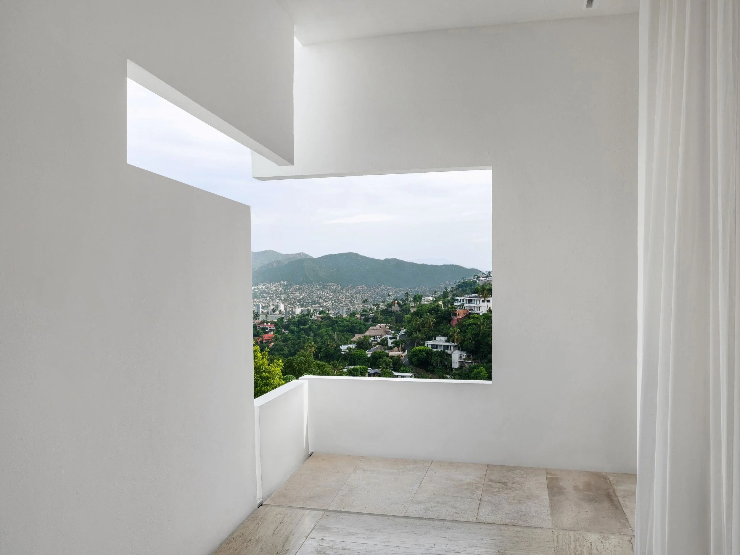 Detalle de encuadre arquitectónico monolítico que atrapa la vista de Brisas Marqués a través de un vano geométrico enfocado hacia la jungla. 