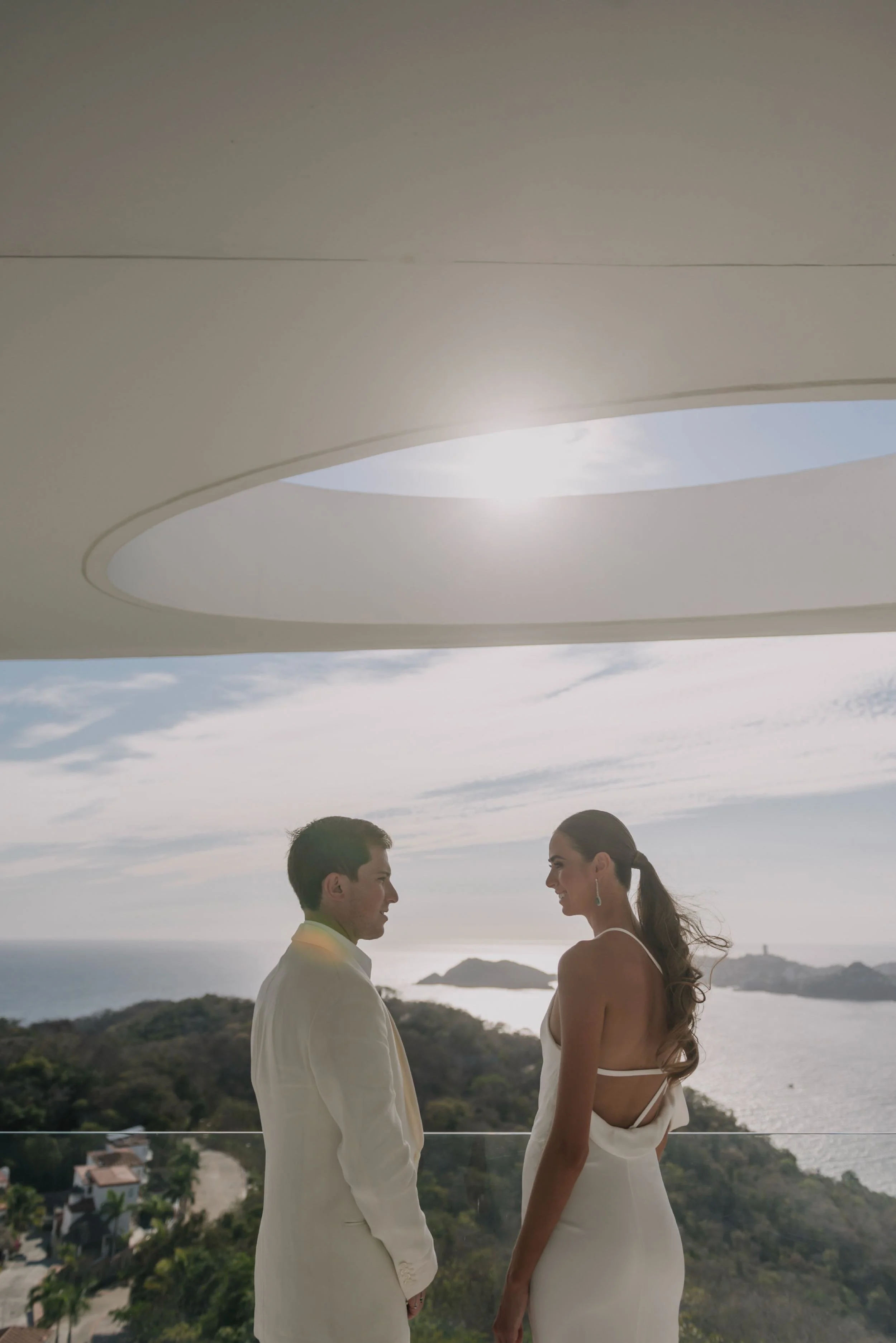 Novios bajo la apertura circular del techo en Hotel Encanto Acapulco. Diálogo sutil de la escala humana con la luz del día.