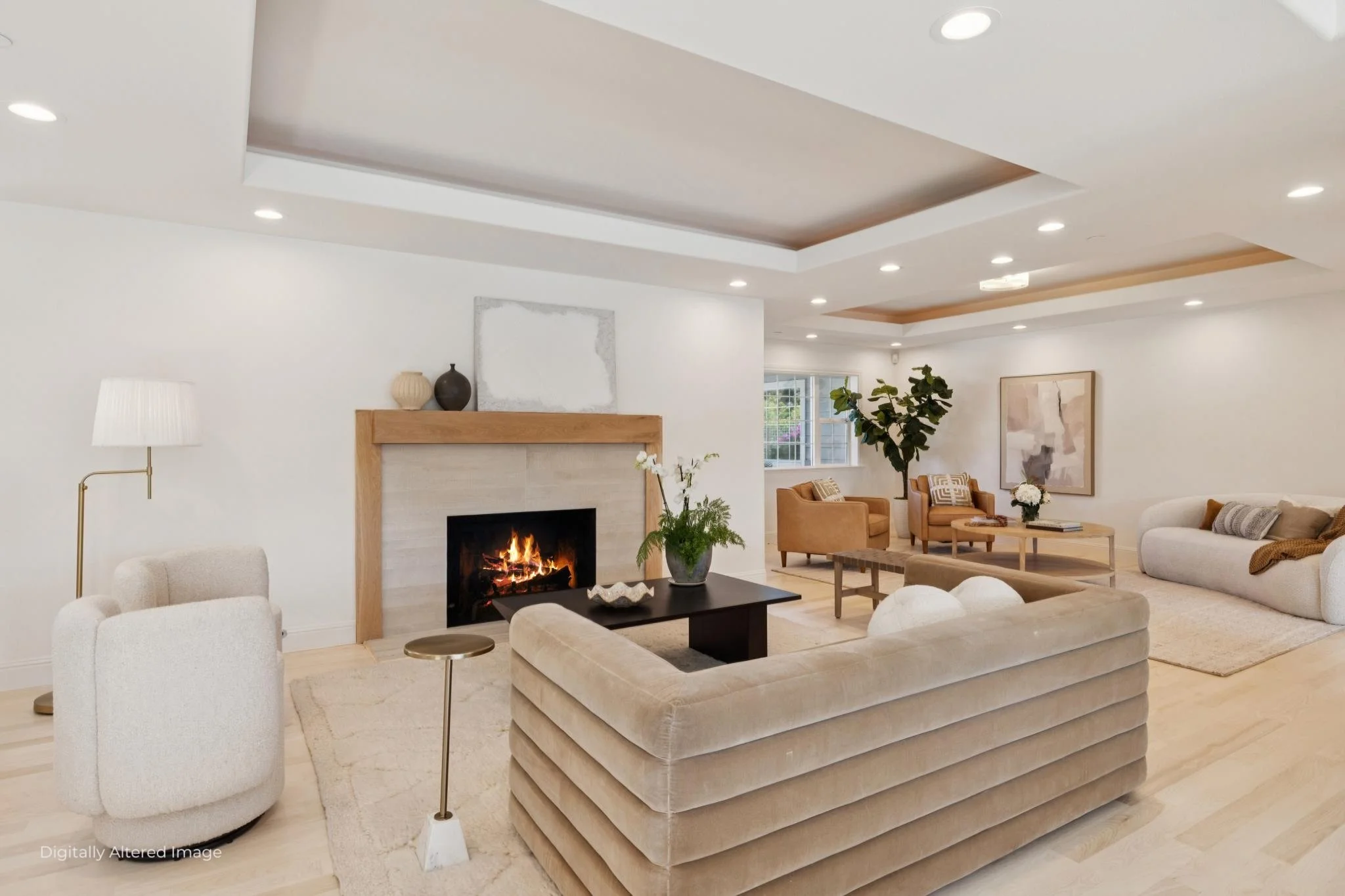 Living room with white walls, beige sofas, a black coffee table, a fireplace, a side table with a lamp, potted plants, and modern ceiling lighting.