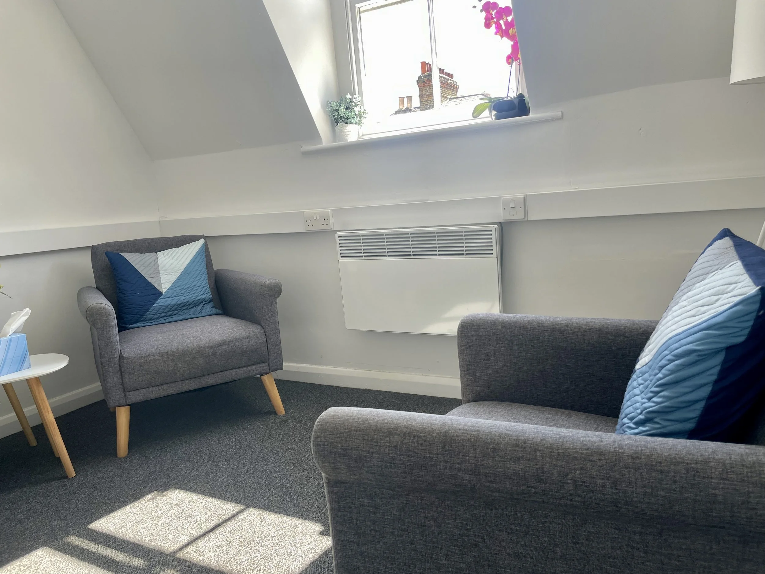 Therapy room at Nilima Choudhury Therapy, Clapham North, South London, showing therapist and client chairs with natural light from the window