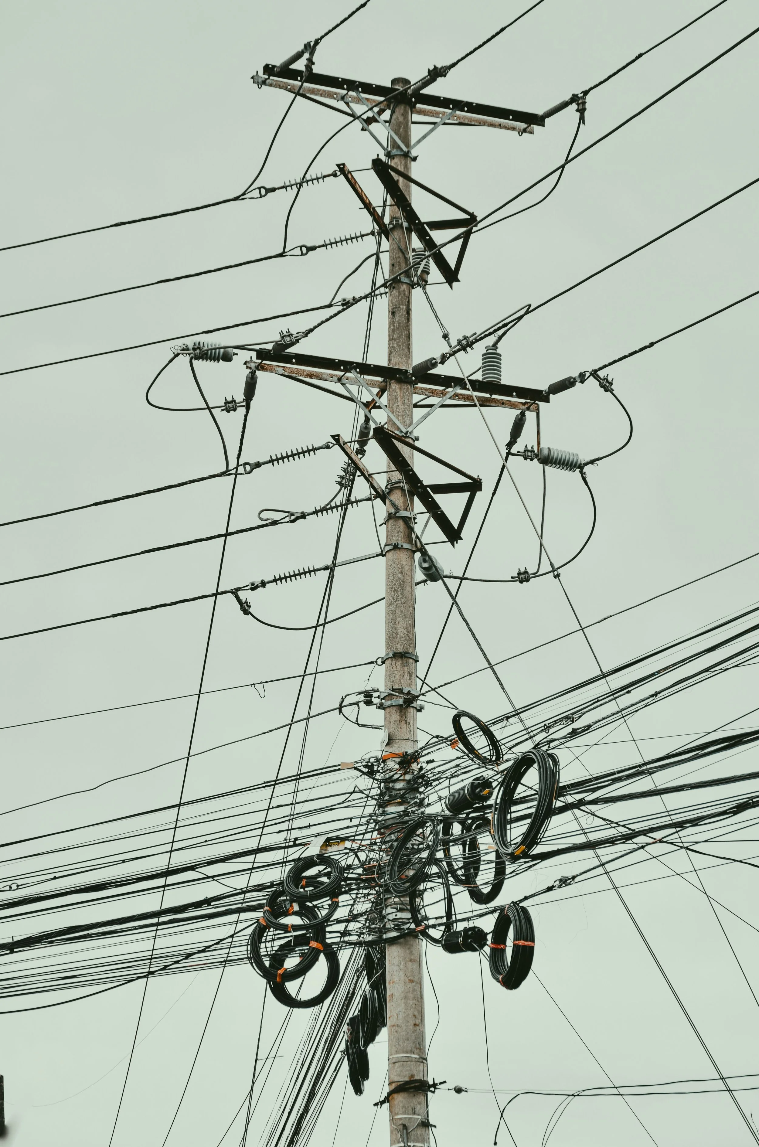 Overhead utility wires and telegraph pole against an overcast sky