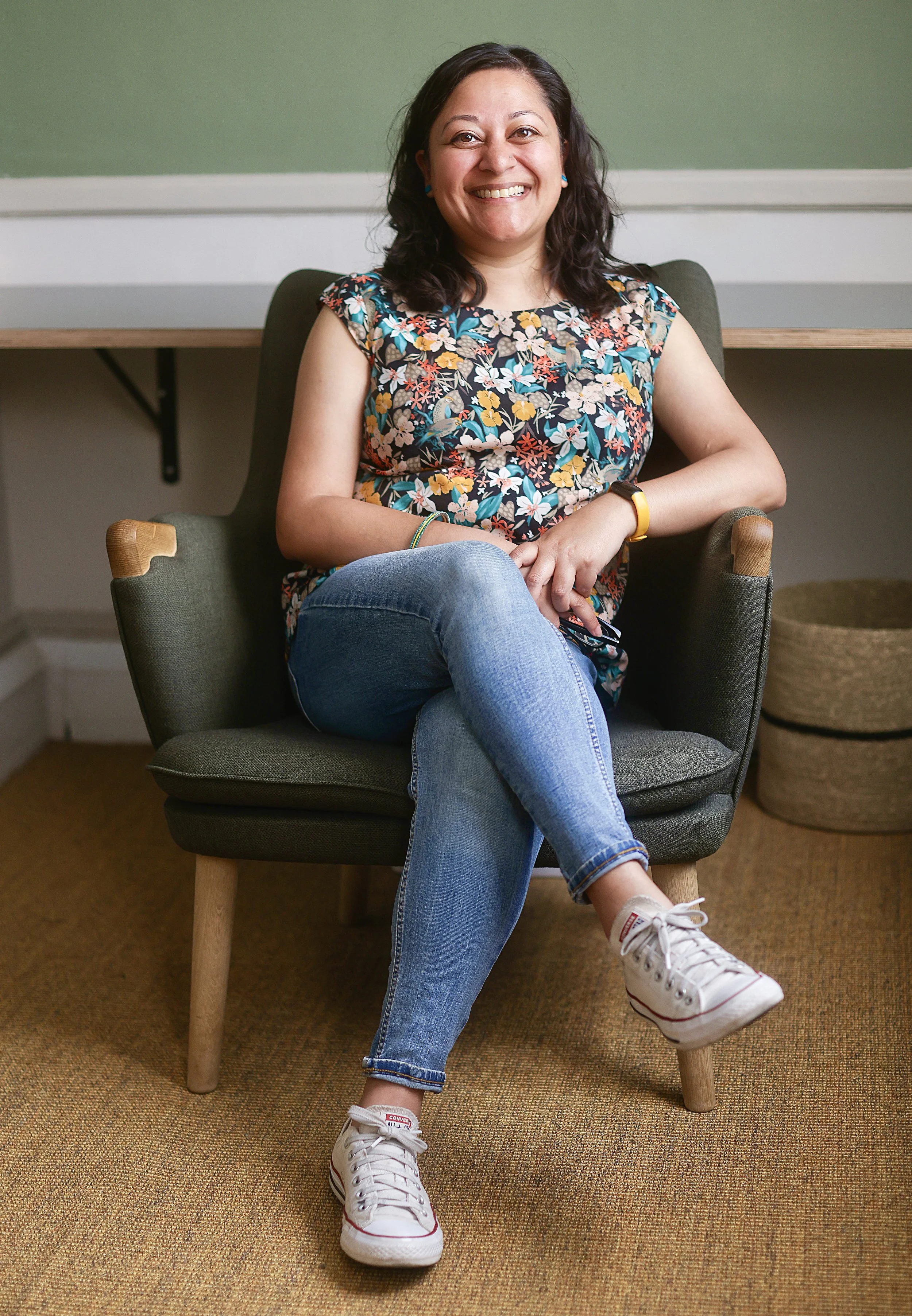 Nilima Choudhury, therapist in Clapham South London, sitting relaxed in a therapy chair wearing jeans and Converse