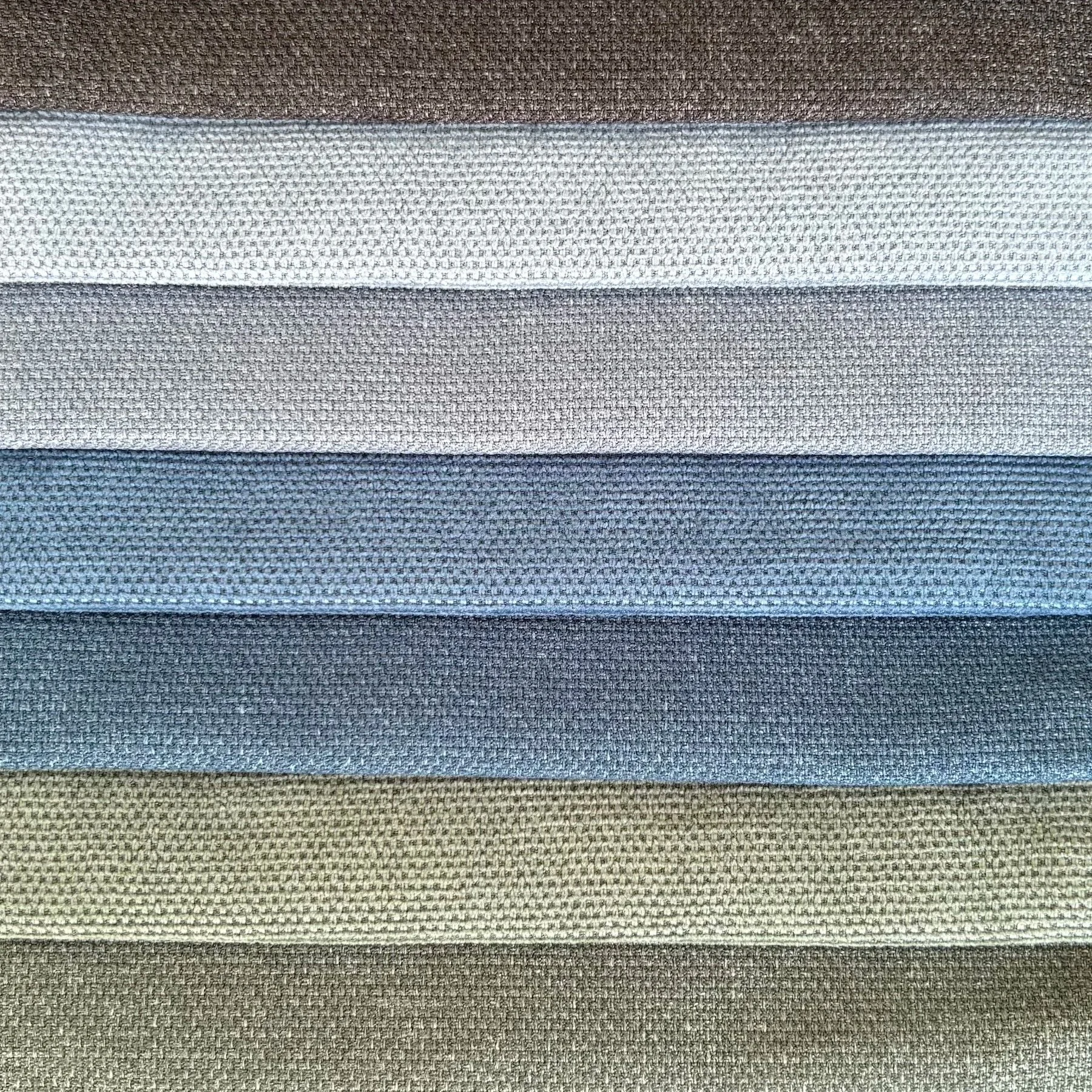 A display of six folded fabrics, ranging from brown at the top to black at the bottom, with various shades of gray and beige in between.