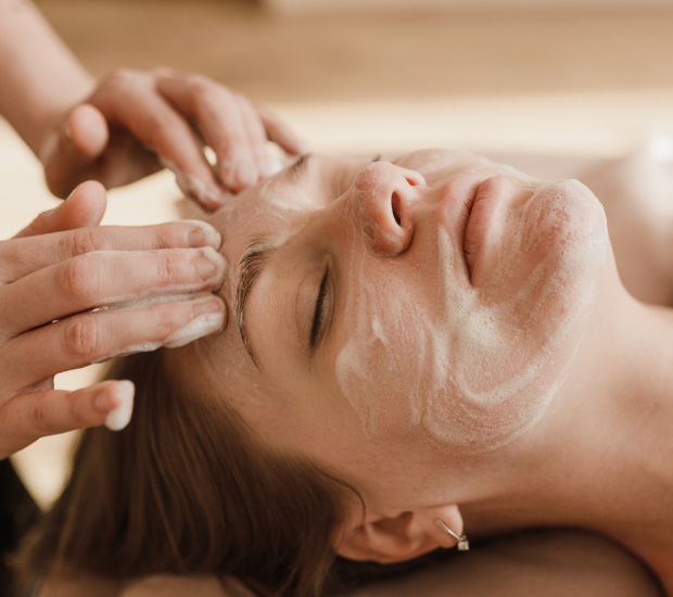 Woman receiving a facial massage with foam skincare product applied to her face