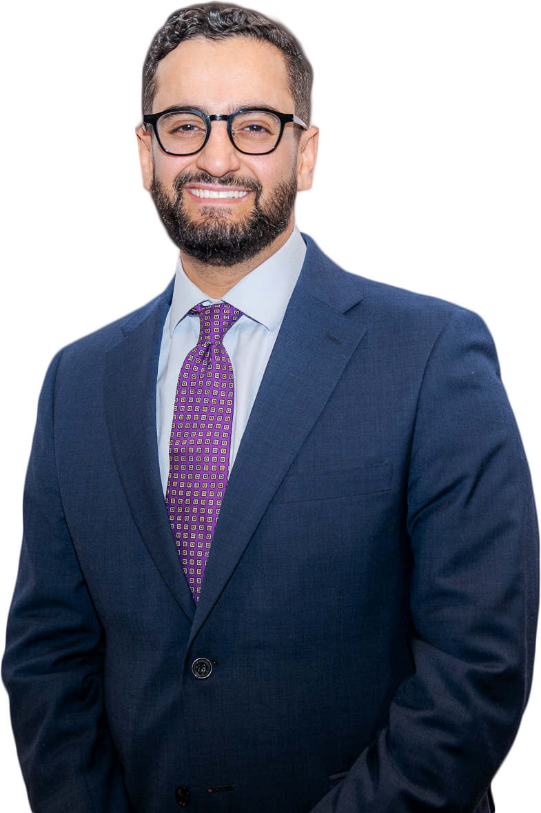 A smiling man with a beard, glasses, wearing a blue suit, light blue shirt, and a purple patterned tie.