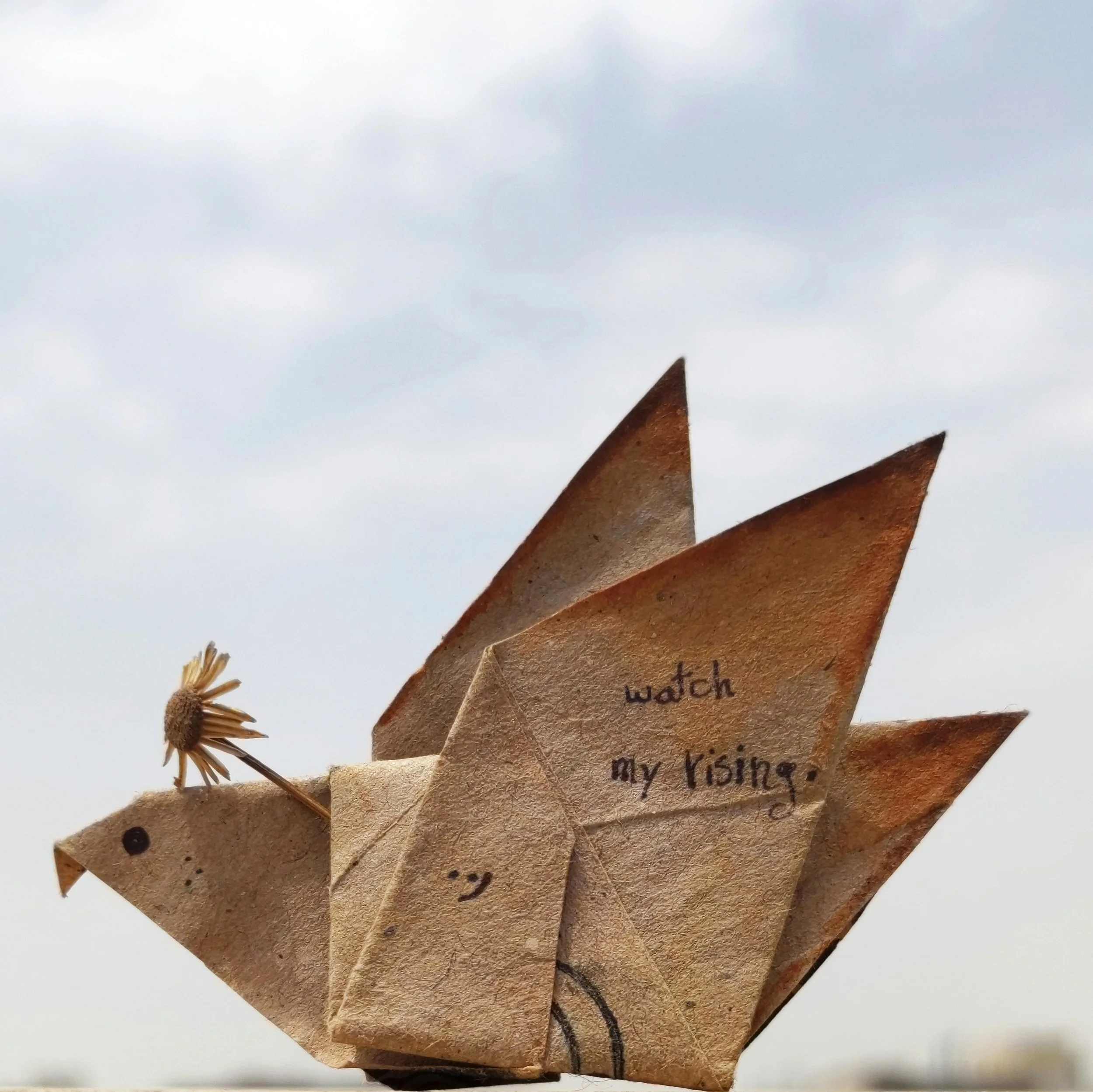 Close-up of a paper craft dragonfly with handwritten text on the wings.