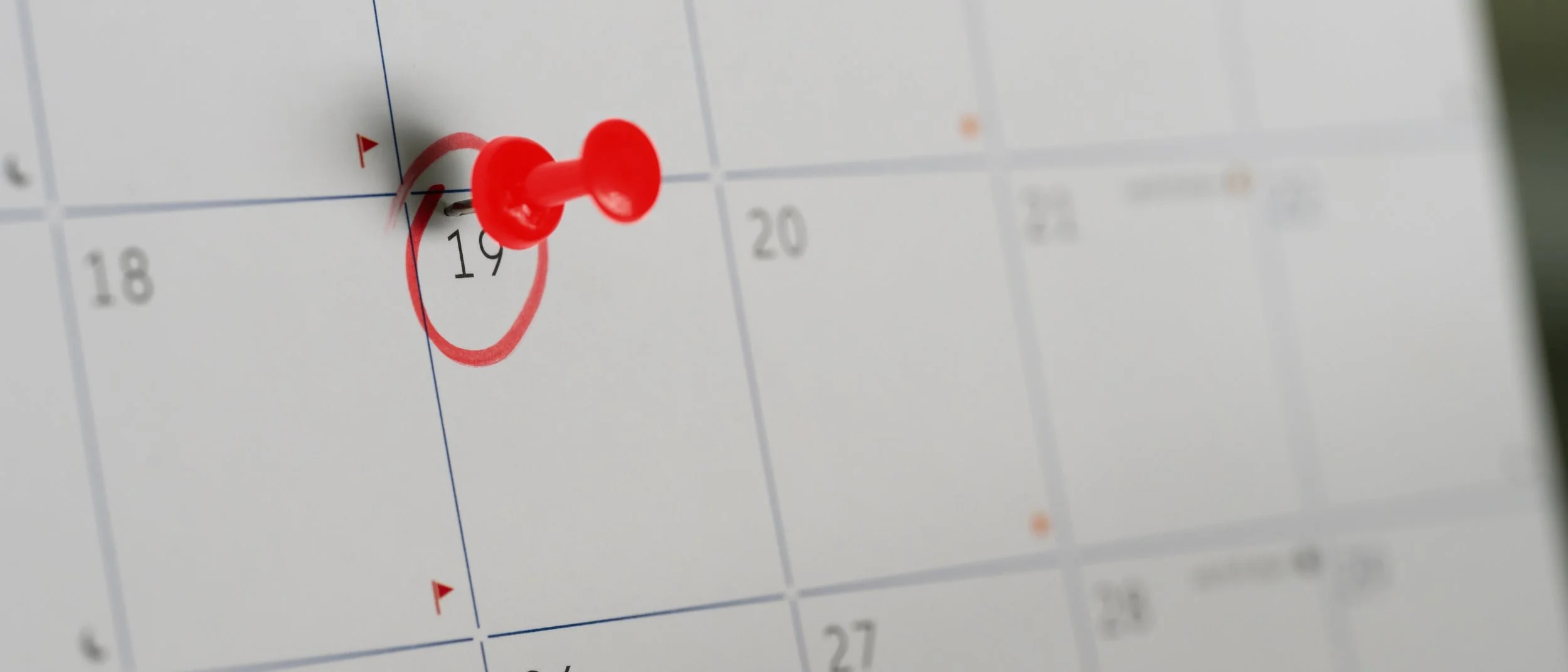 A close-up of a calendar with a red pushpin marking March 19th, with the date circled in red.