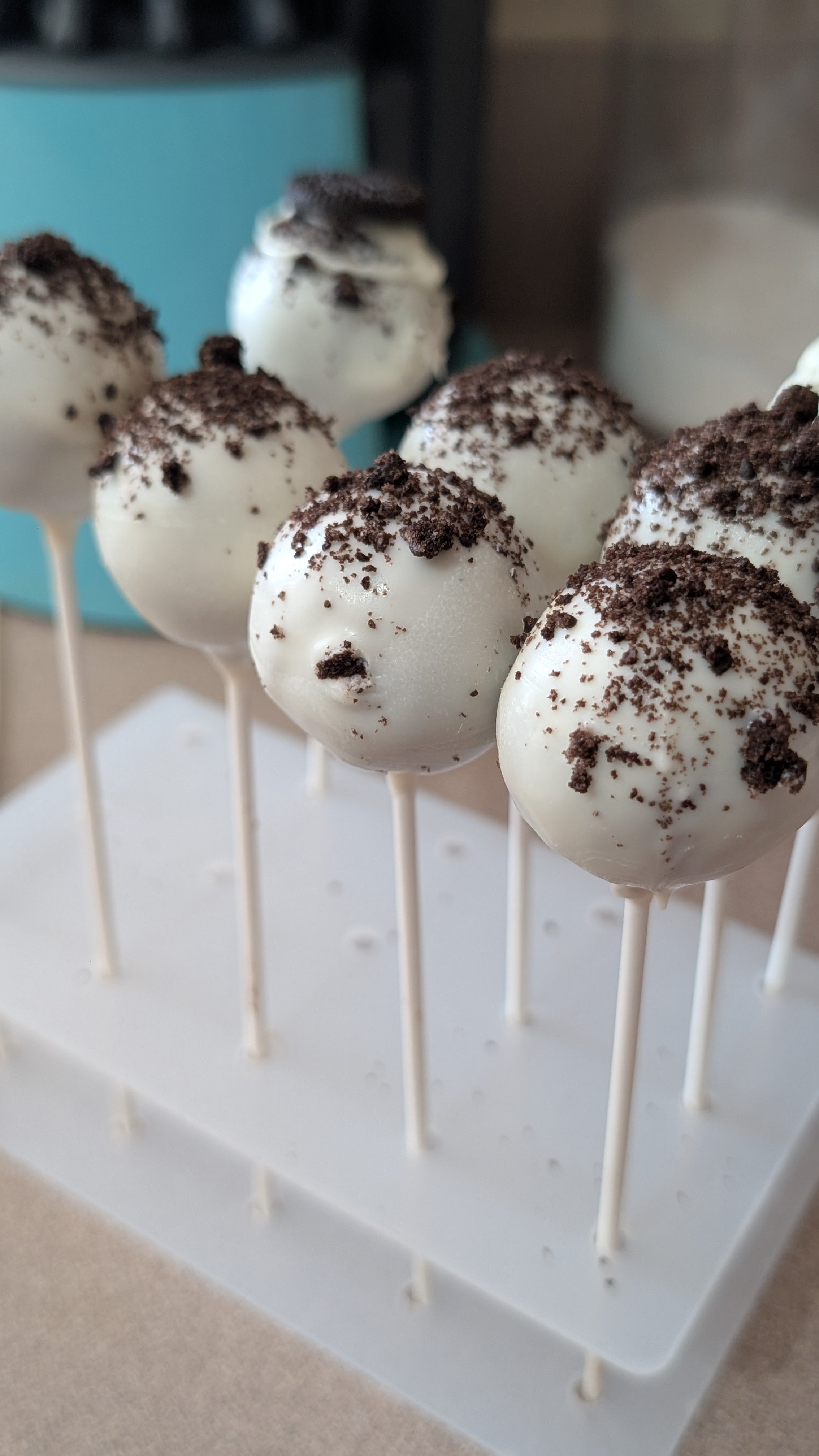 Cake pops with vanilla coating and crumbled chocolate cookie topping on white sticks