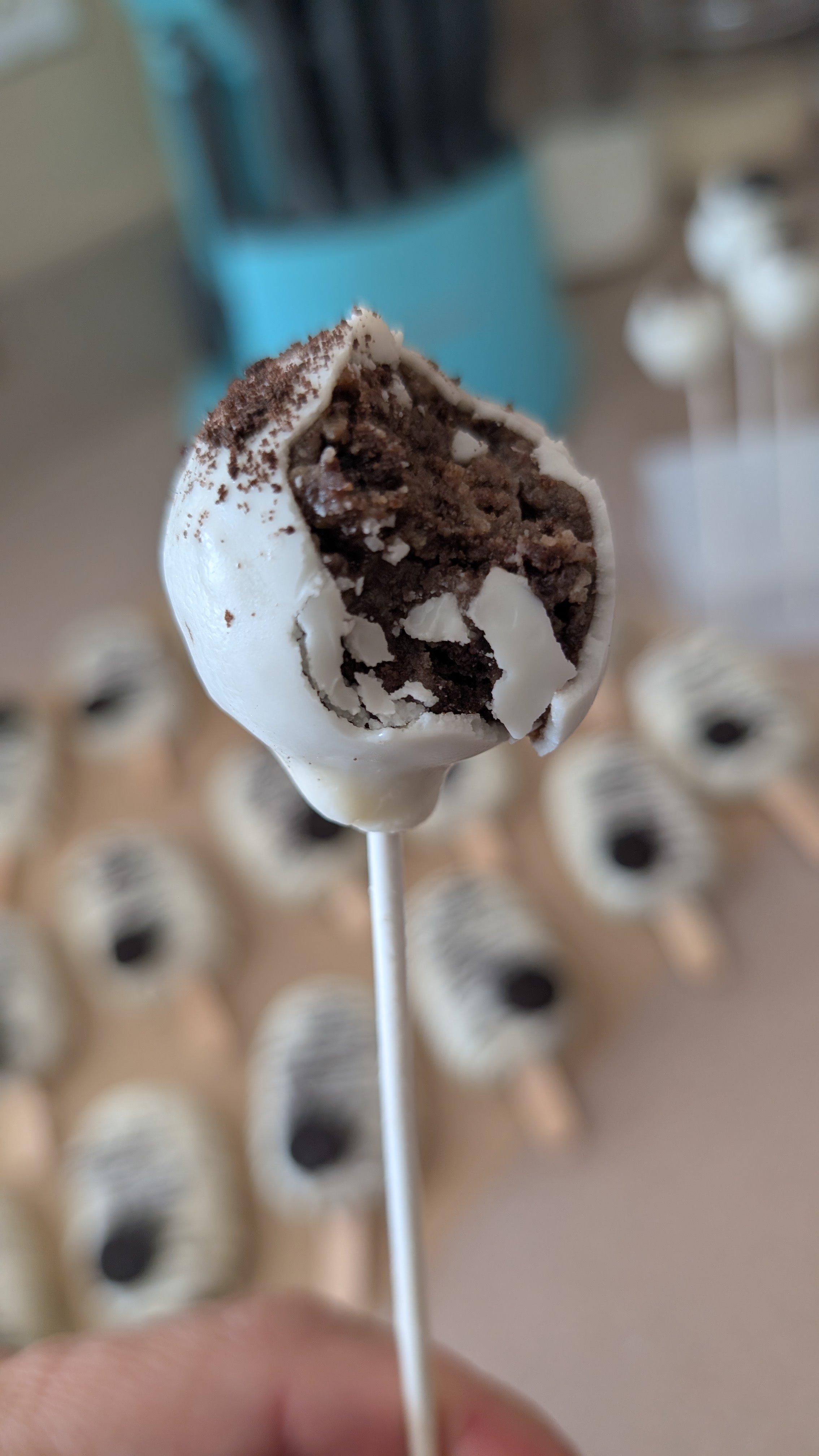 Close-up of a chocolate and vanilla ice cream bar on a stick, with a bite taken out of it, held in front of a background of identical ice cream bars.