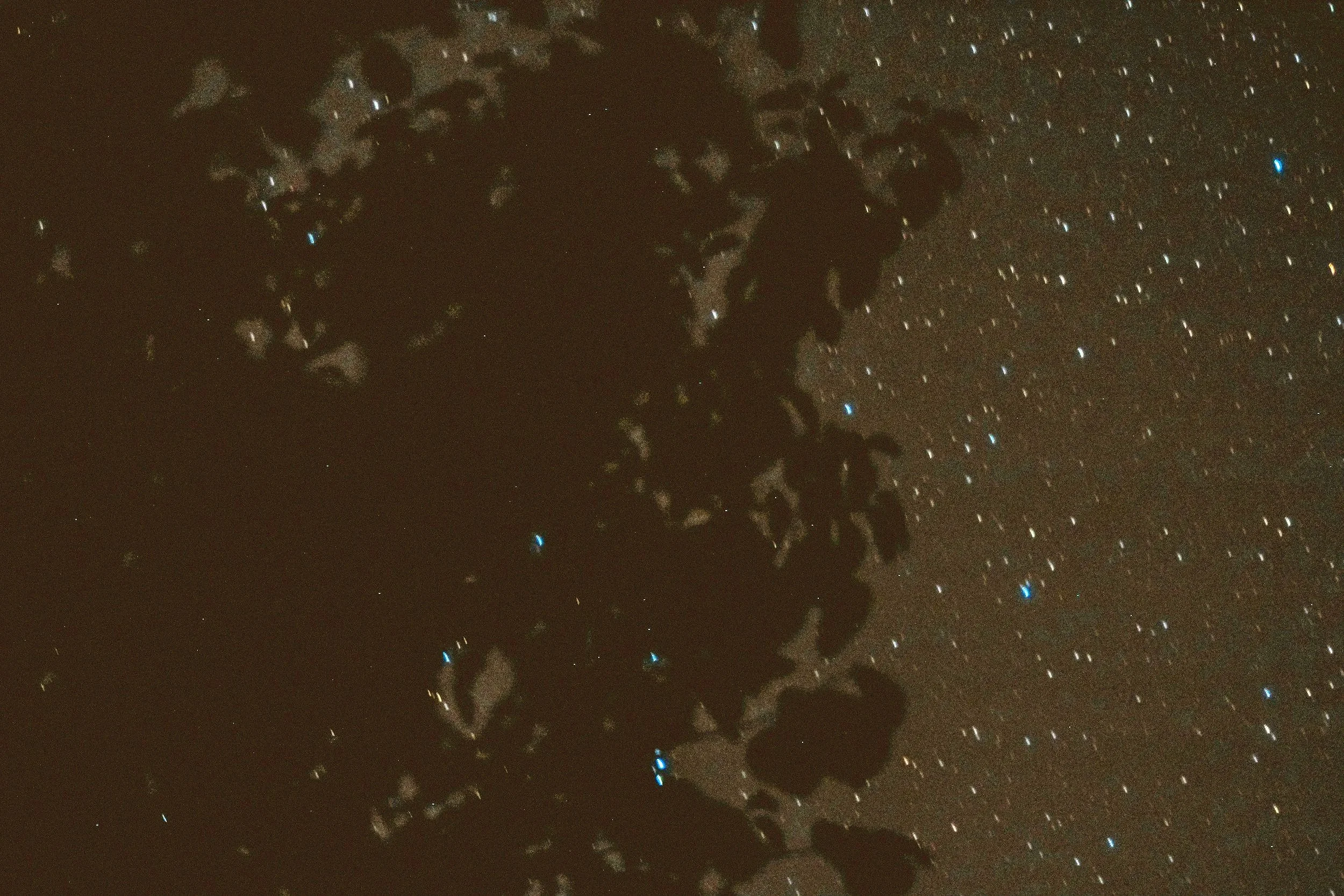 A silhouette of a person standing on a rocky landscape, gazing at a vibrant display of the Milky Way galaxy across a dark sky filled with countless stars.