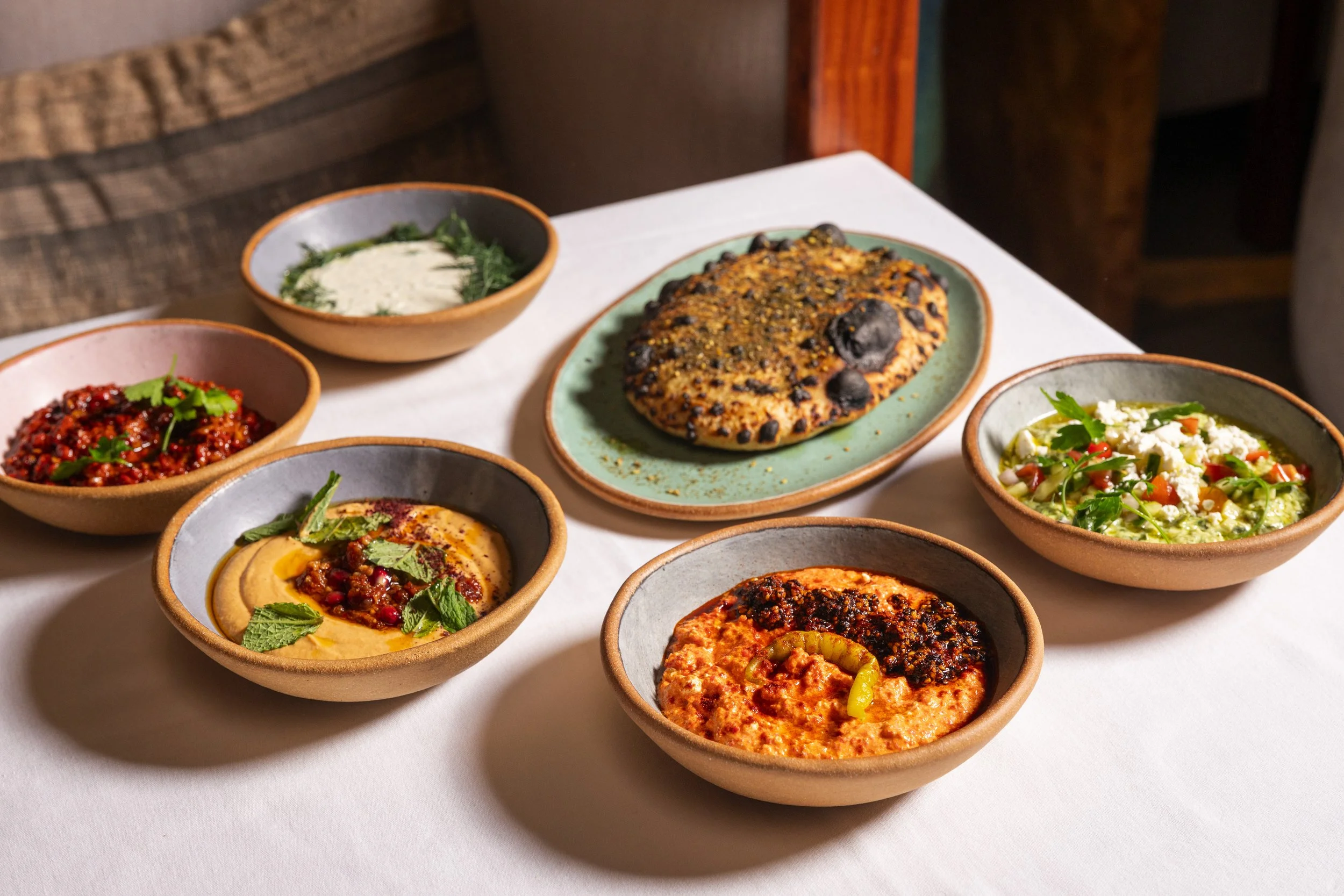 Assorted Indian curries and dishes served in small bowls on a white tablecloth.