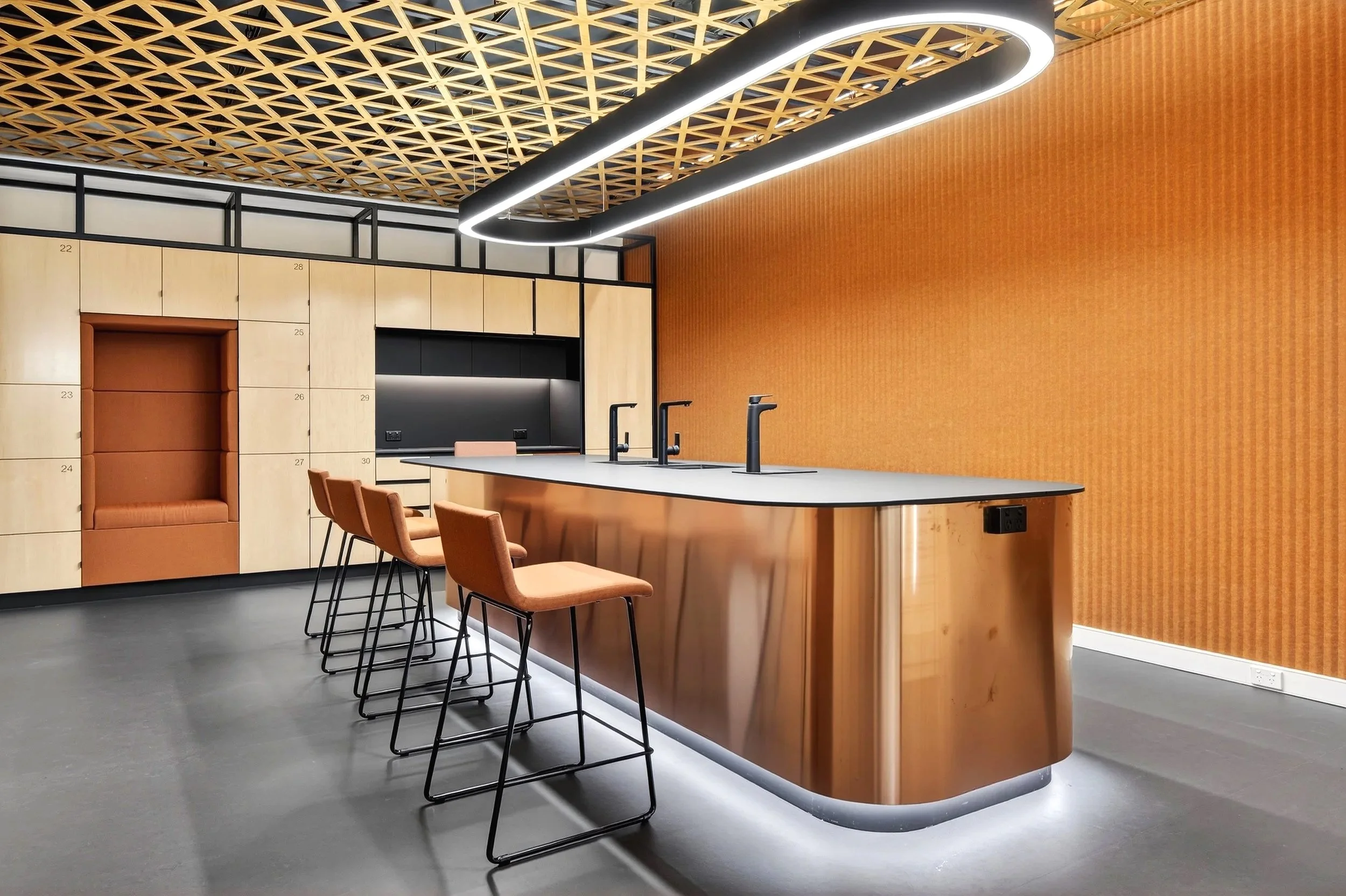 Modern kitchen with a curved island, four peach-colored chairs, wooden cabinetry, and a decorative wood lattice ceiling with integrated lighting.