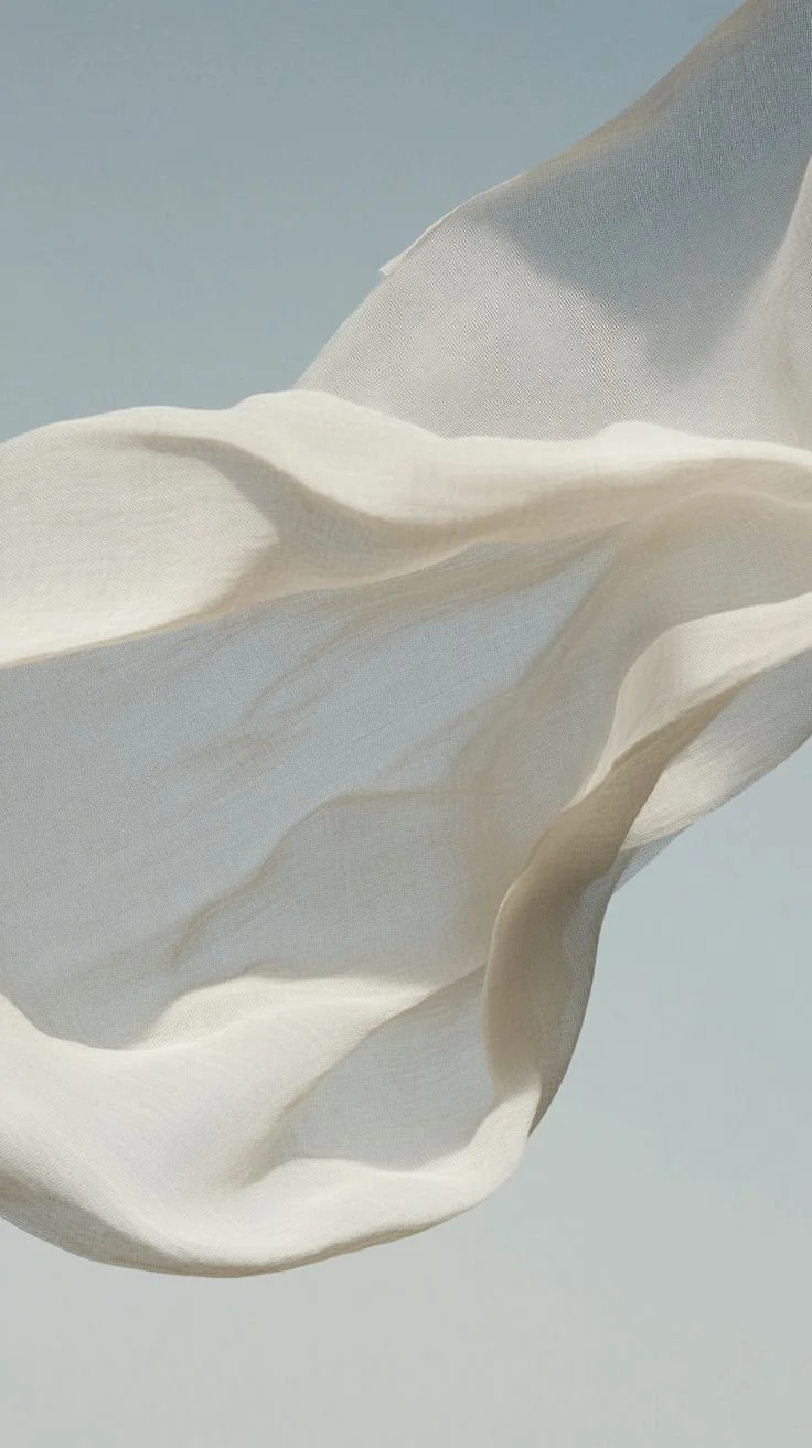 Close-up of a flowing, semi-transparent white fabric against a plain background.