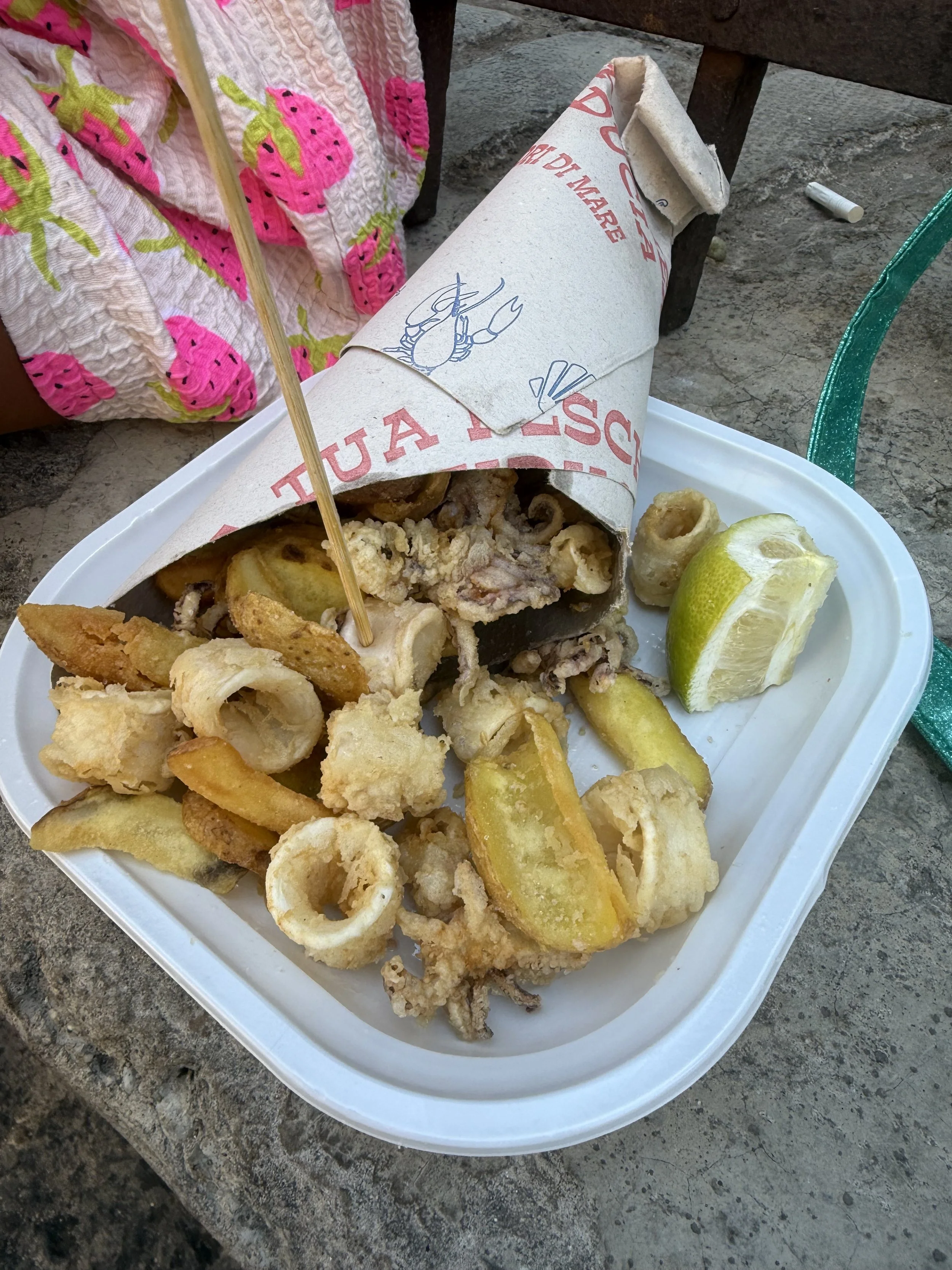 Fried seafood platter from Calabria Southern Italy Food Tour with lemon wedges on a white tray, placed on a stone surface.