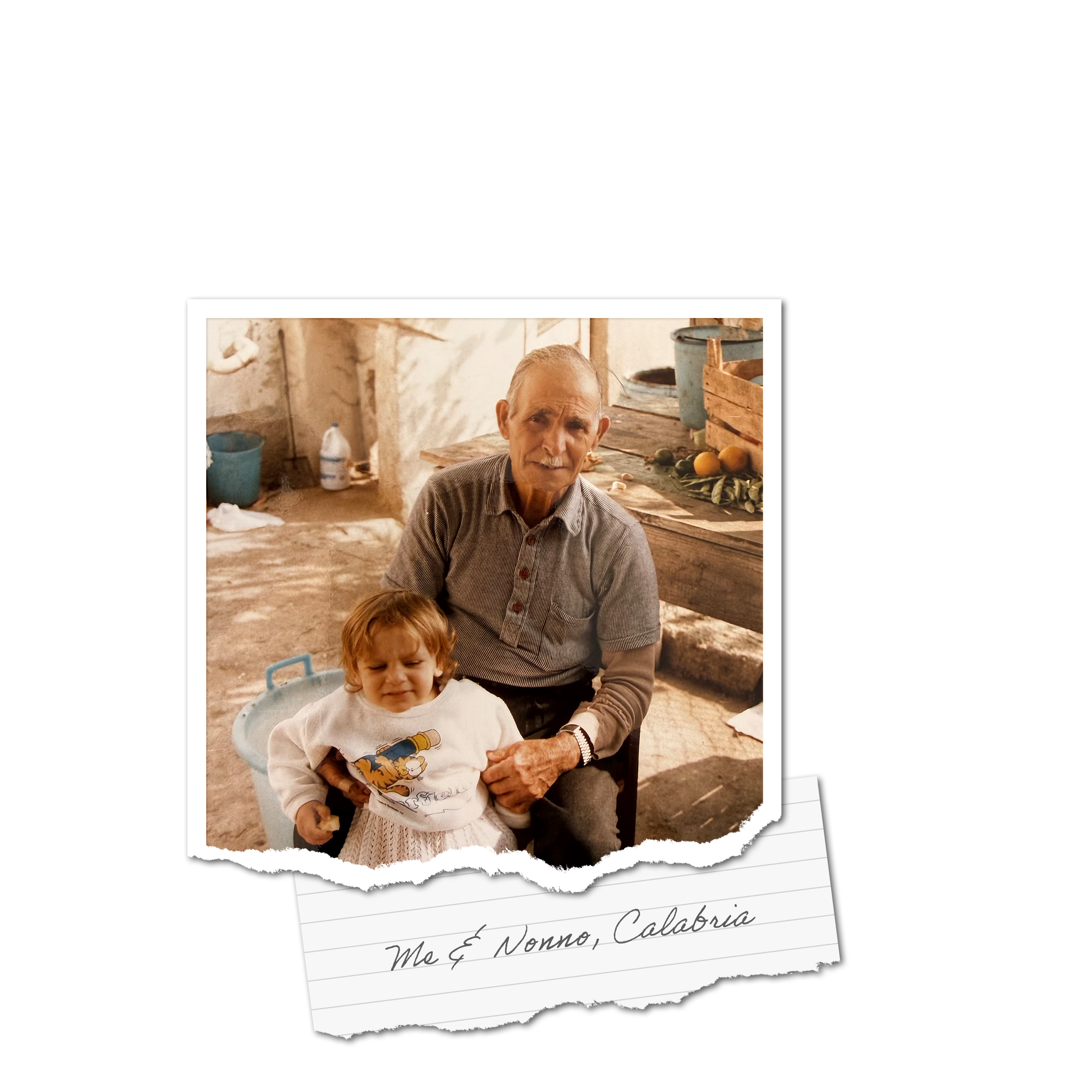 A close-up photo of an elderly man with white hair and mustache, and a young girl with curly red hair, both smiling. They are sitting outdoors with rustic buildings and fruits like oranges and mangoes visible on a table behind them. The photo is overlaid on a white, torn-edge paper with handwritten text reading "Italy Me & Nonno, Calabria".