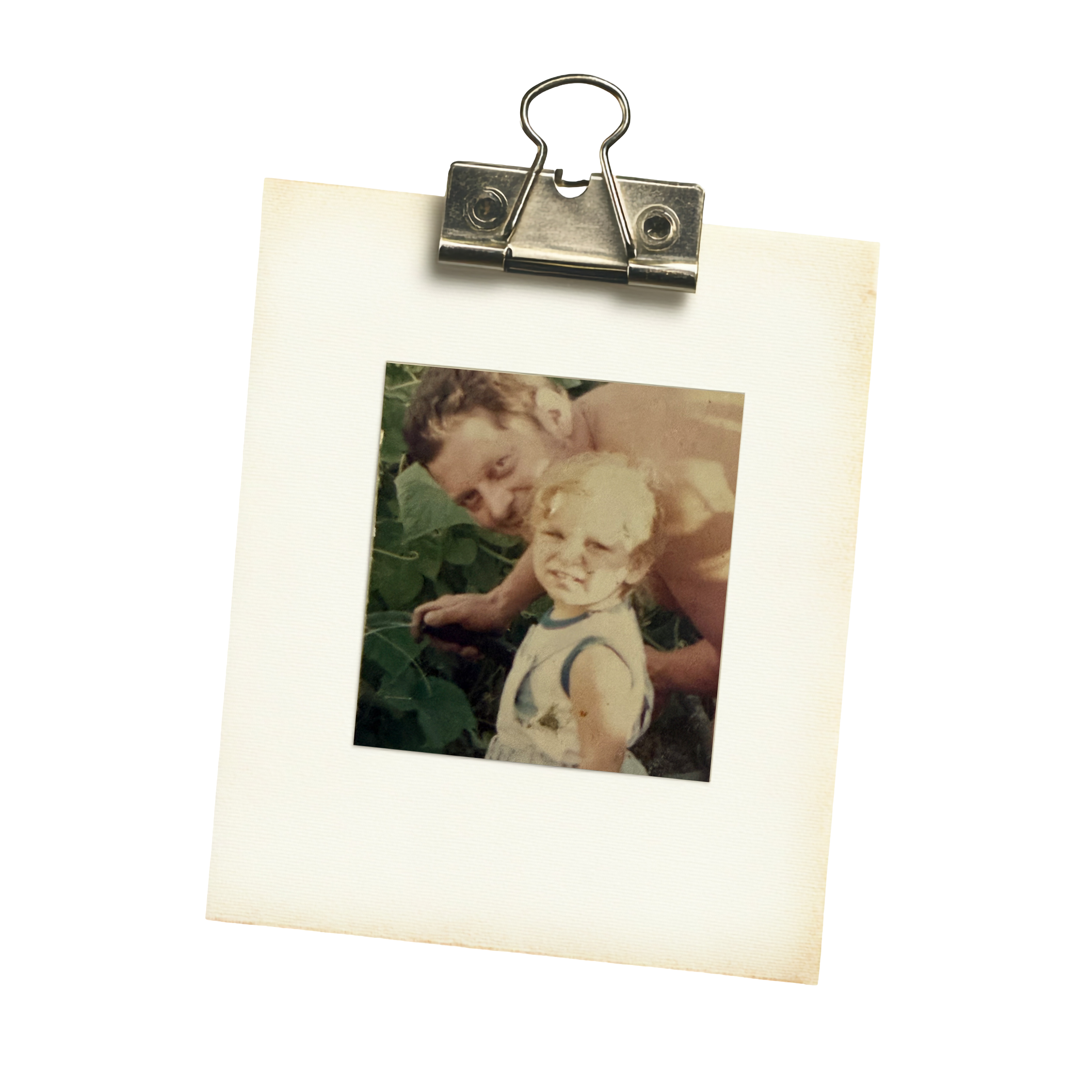 Close-up of a metallic clipboard clip holding a photograph of a child with a dog, attached to a blank polaroid frame.