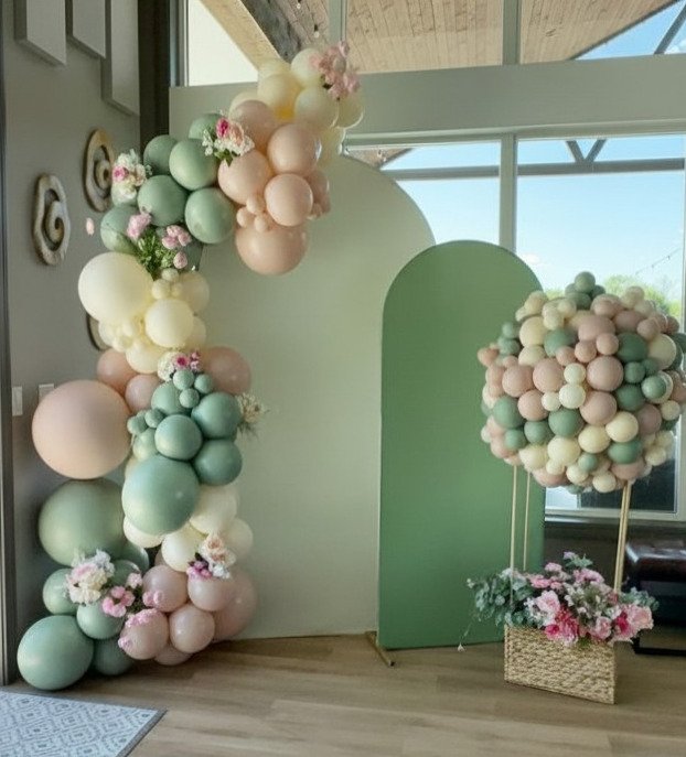 Decorative balloon arch and arrangement with pastel-colored balloons and flowers in a modern interior space.