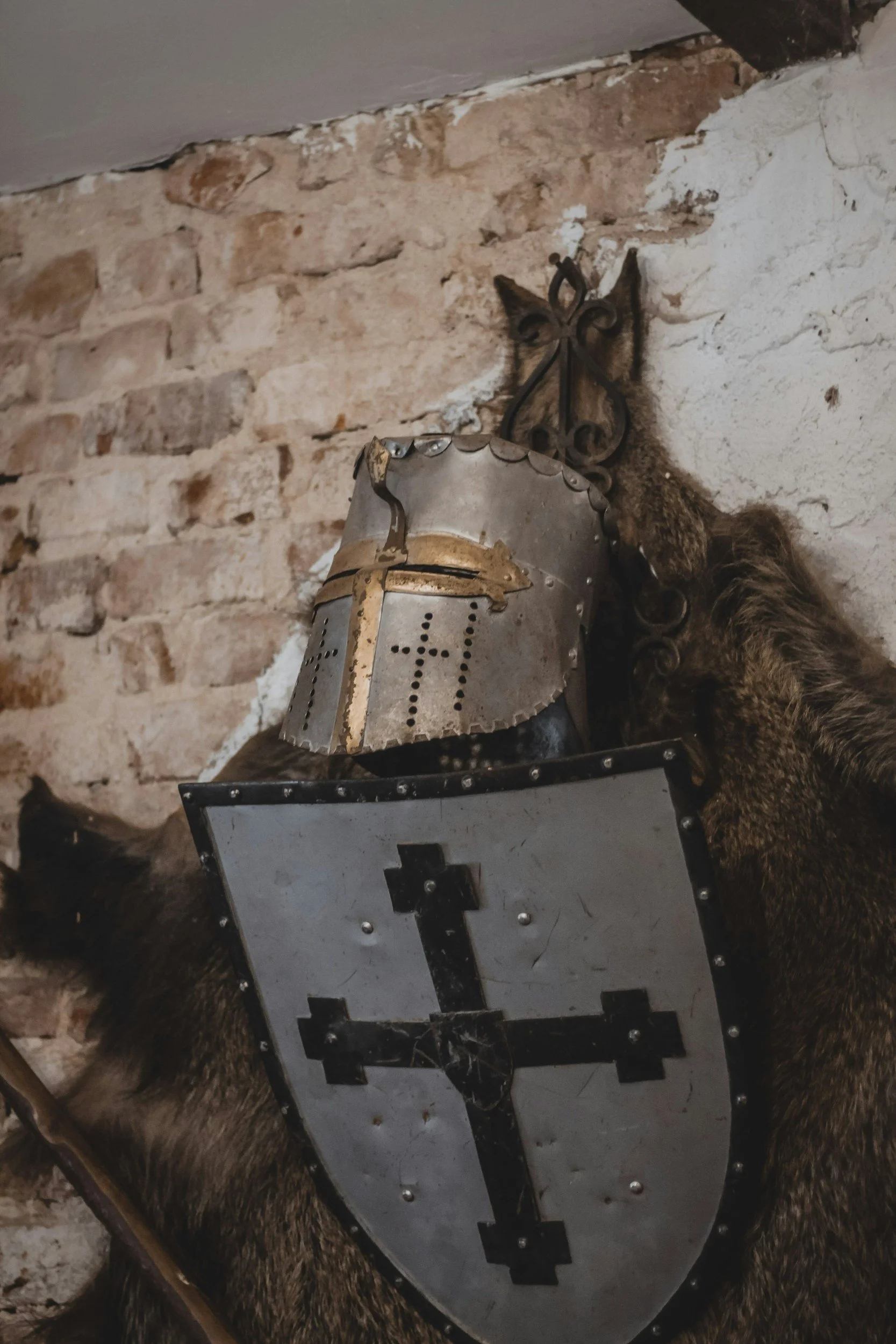 A mounted fox head with a letter Q on its forehead, a coin slot, and a cross symbol on the front, set against a brick wall.