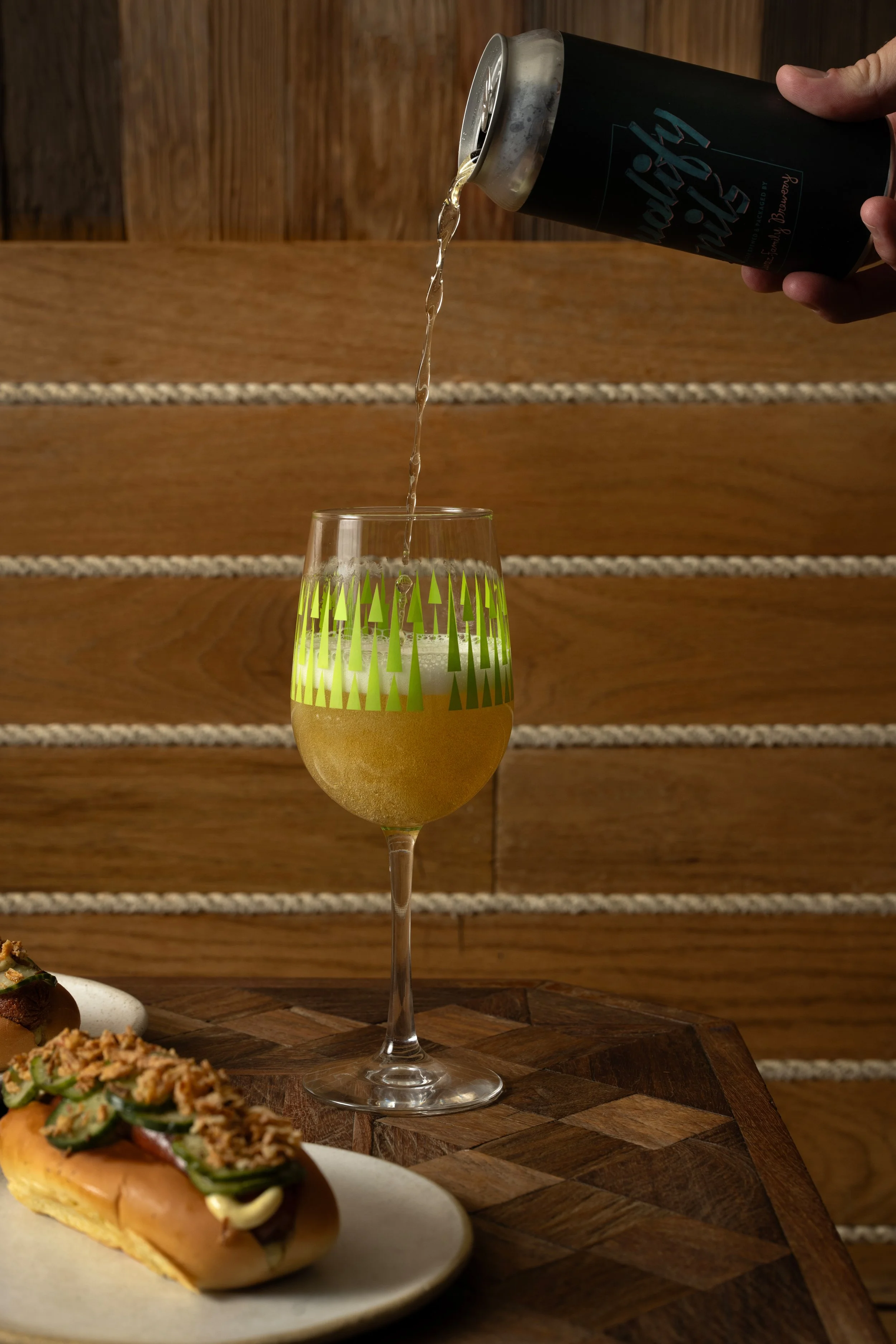 Beer being poured from a can into a green patterned Tørst glass, with a Danish dog in the foreground