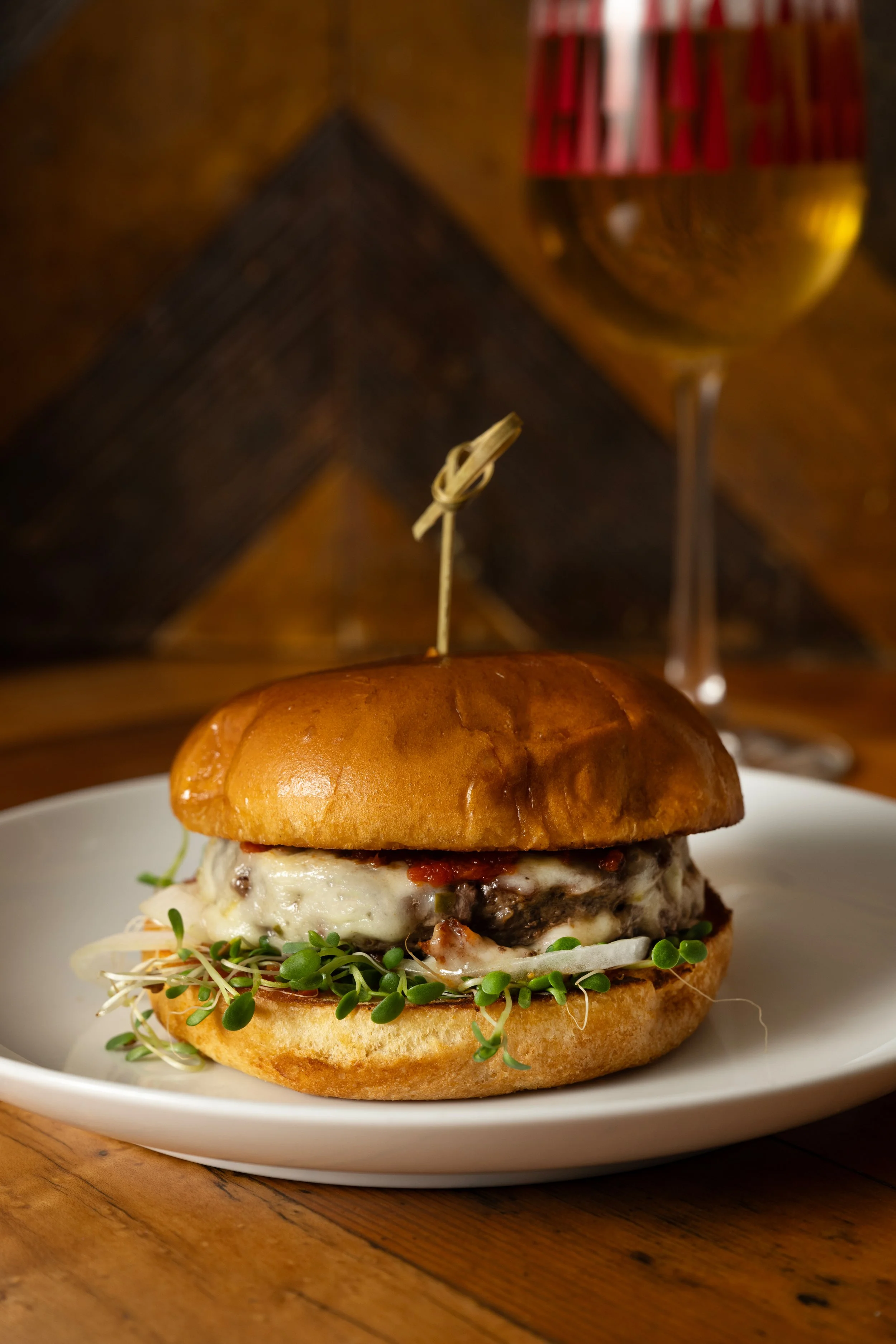 Dry-aged Pat LaFrieda burger with pepperjack, smoked tomato jam, sprouts, and onion on a toasted brioche bun, served with a beer