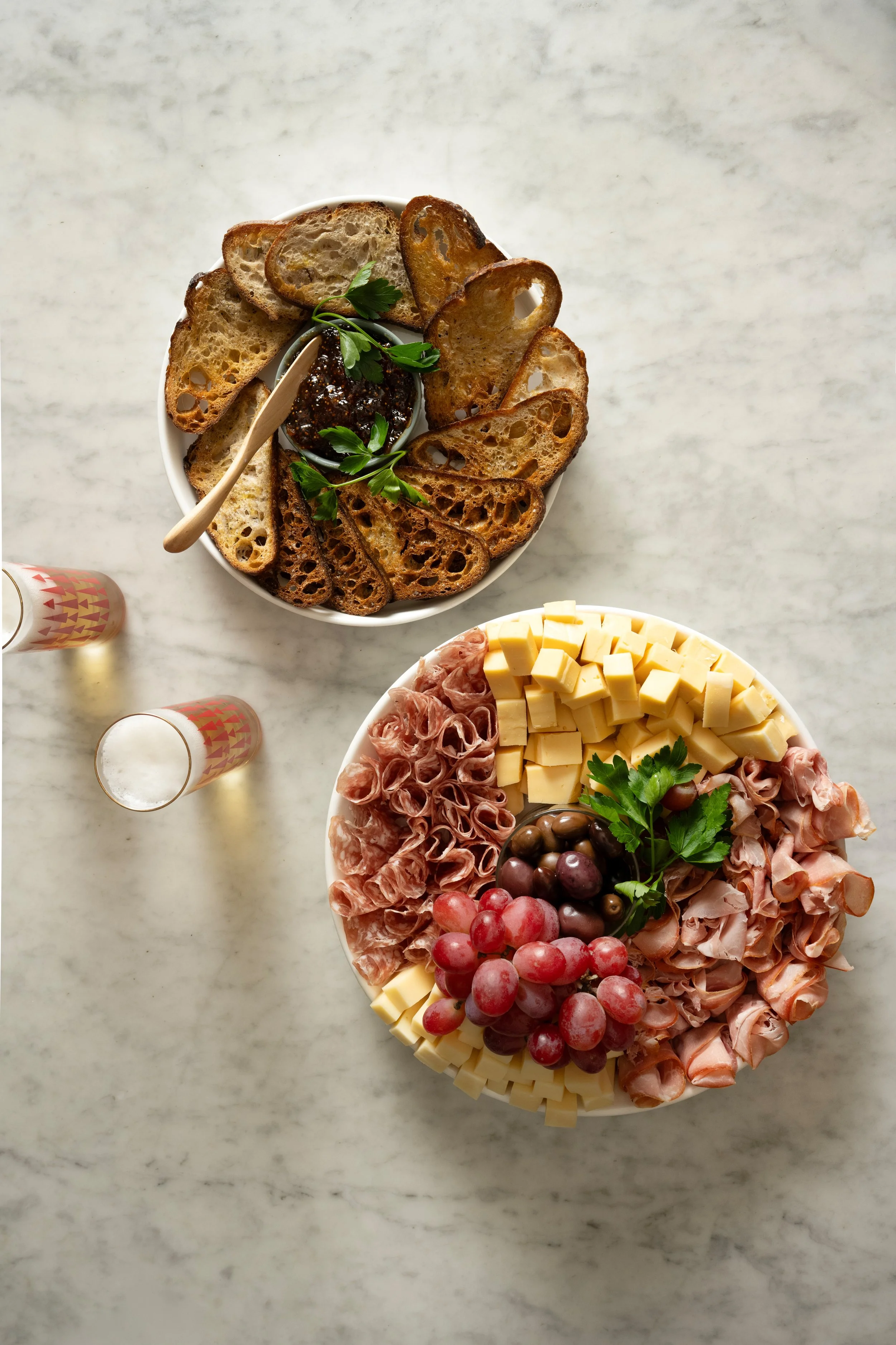 Overhead view of Tørst's cheese and charcuterie platter with cured meats, grapes, and olives alongside sourdough toast and jam