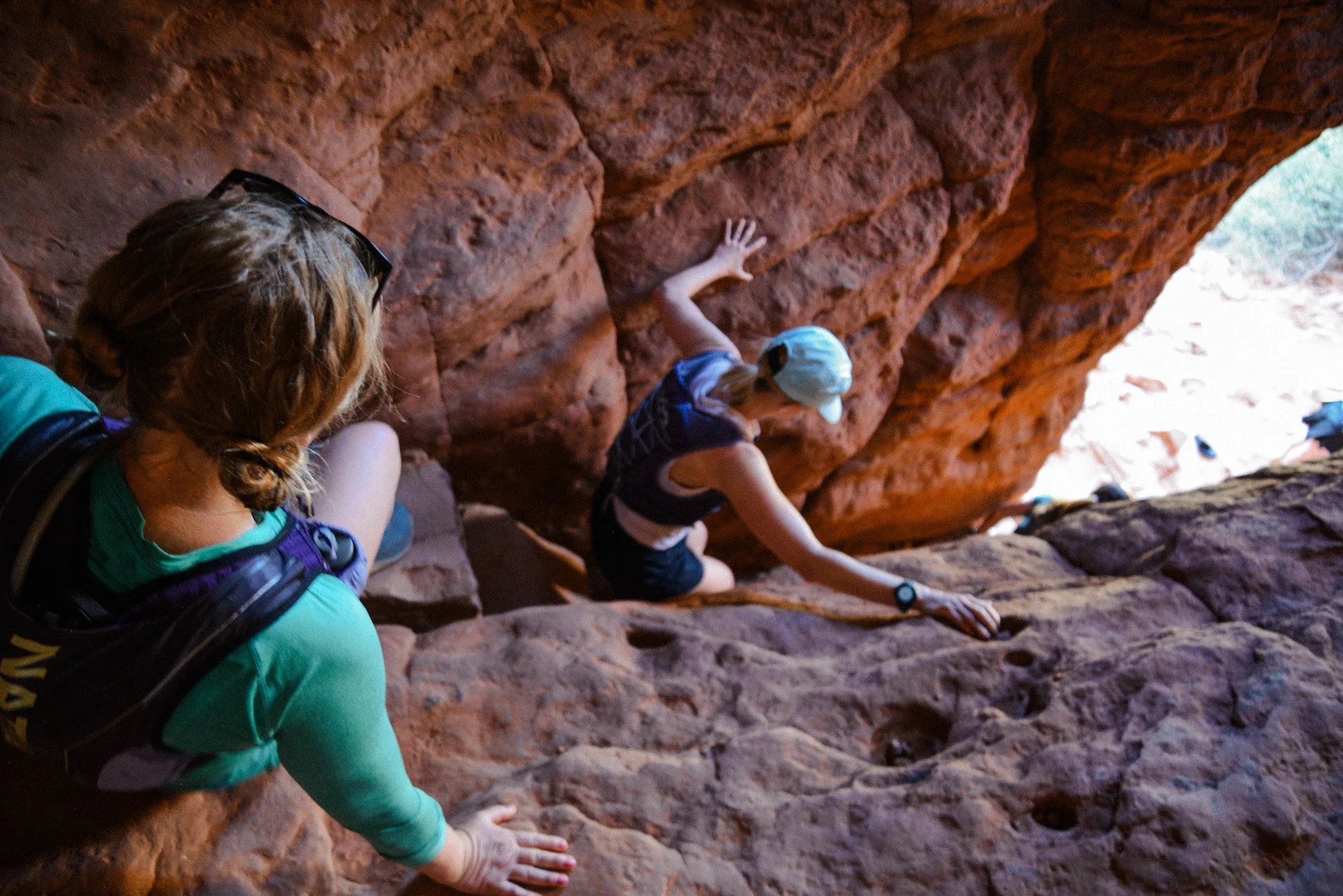 People rock climbing on a red sandstone cliff in an outdoor setting