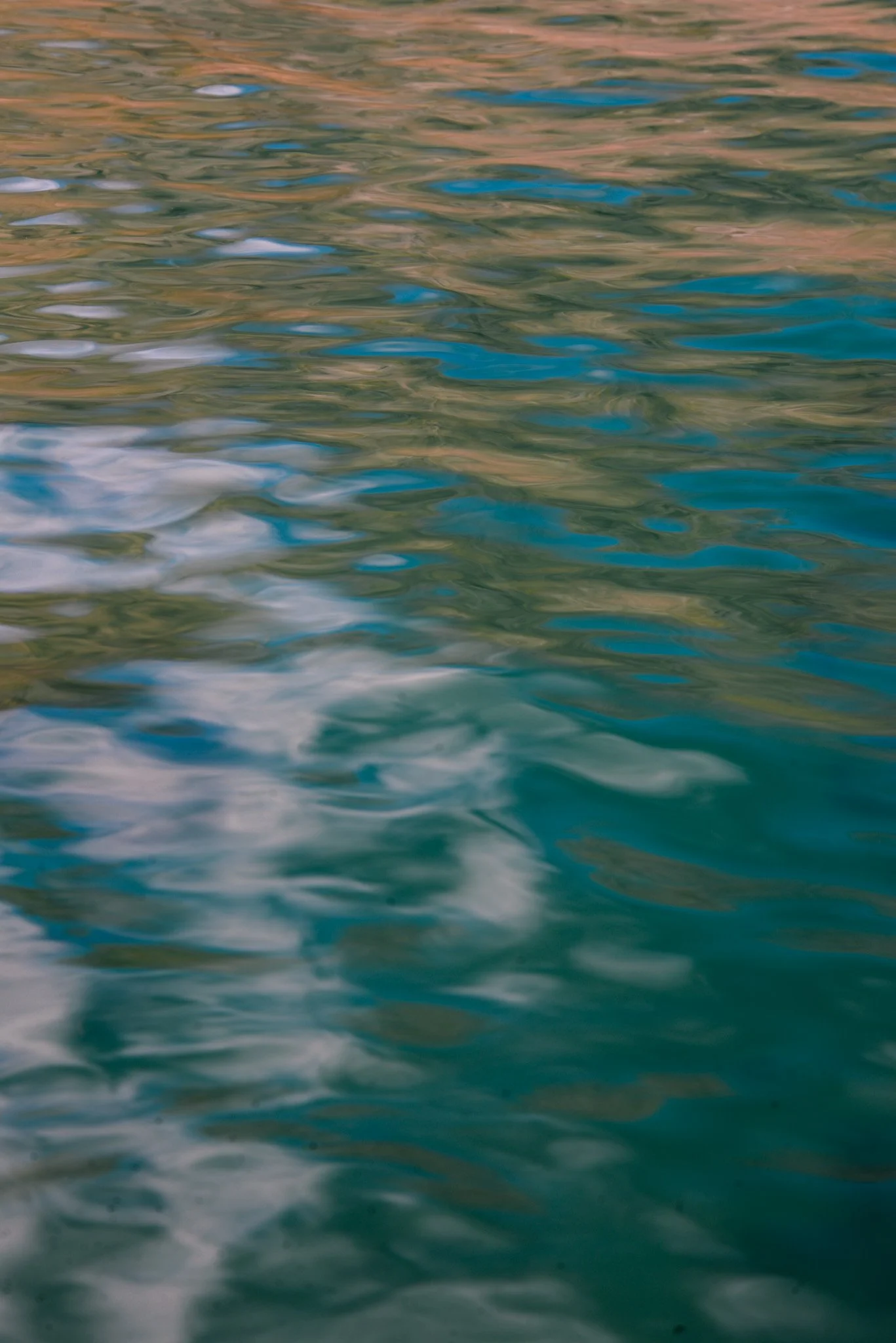 Reflection of colored buildings and sky on the rippling water surface.