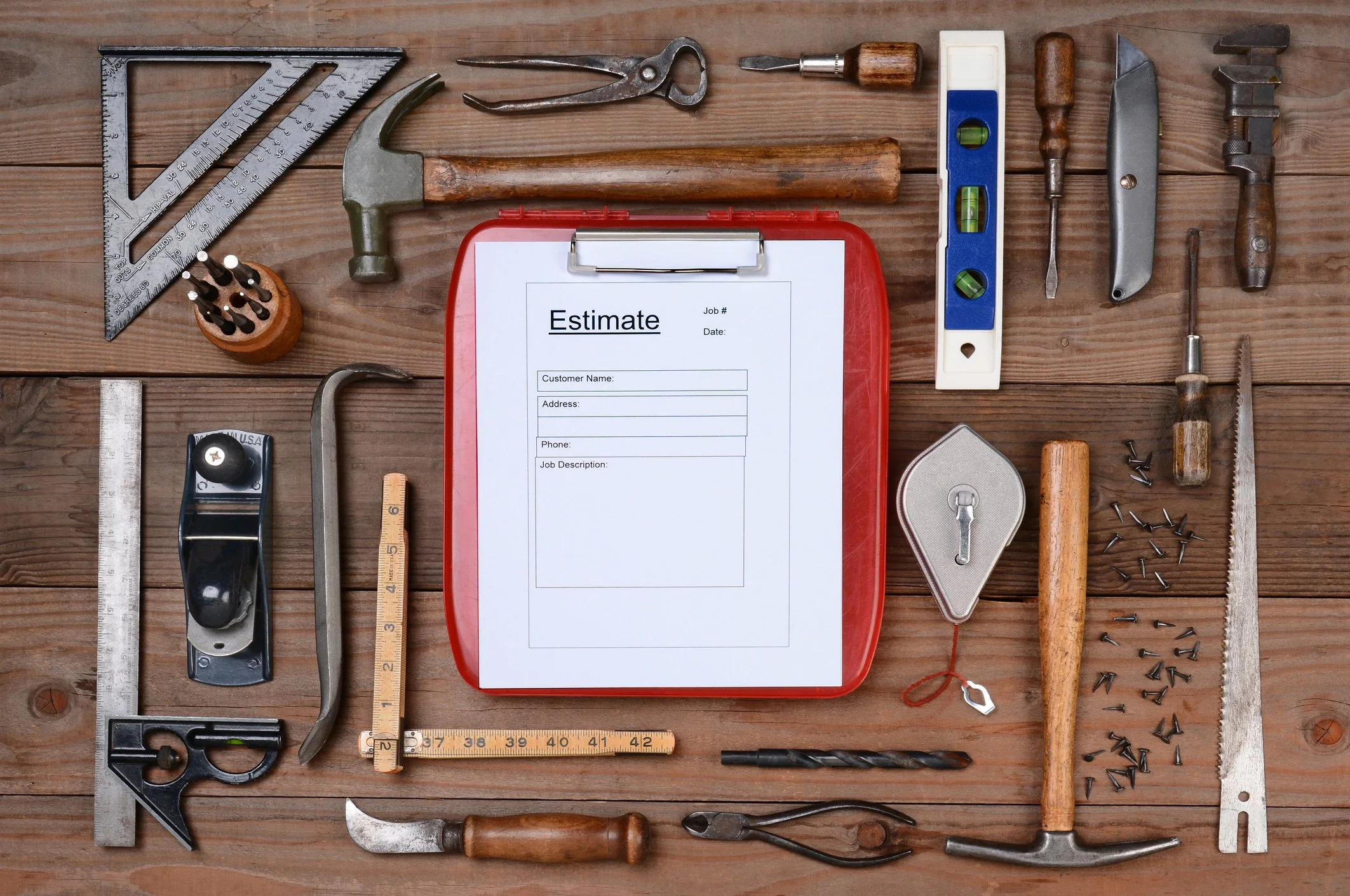 A flat lay of various tools and a red clipboard with a document titled 'Estimate' on a wooden surface.