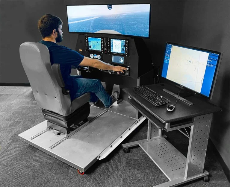 A man seated at a flight simulator cockpit with multiple screens and control panels, positioned in front of a large screen displaying an aerial view for flight training.