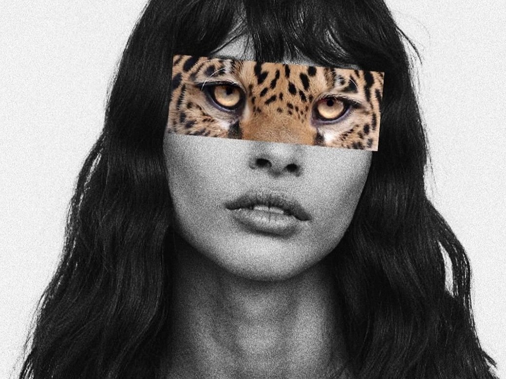 A black and white portrait of a woman with long wavy hair and a leopard's eyes covering her eyes.