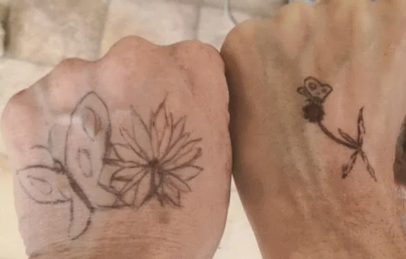 Two hands with drawings, one with a butterfly and flower, the other with a butterfly.