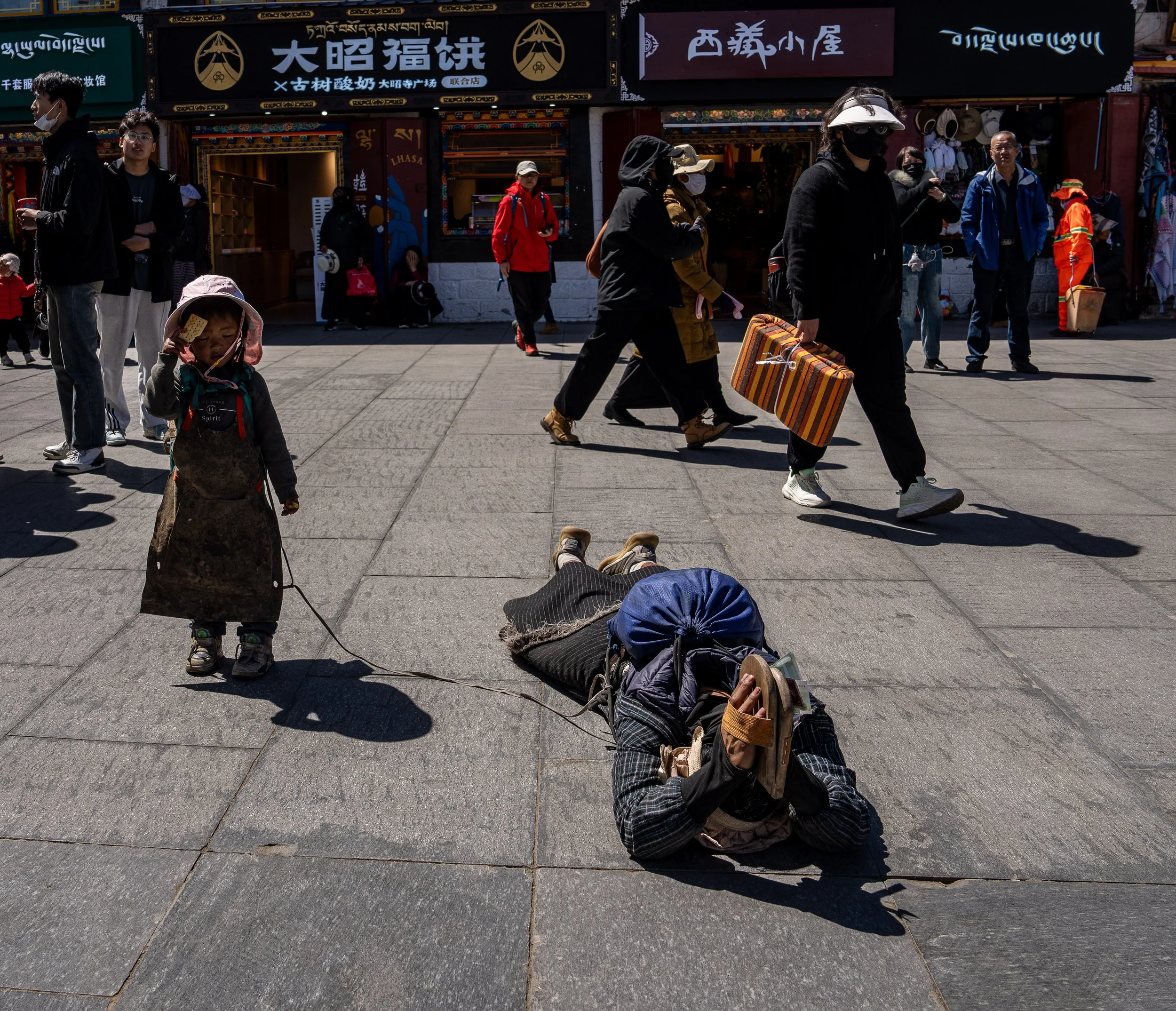 In Tibet a young mother performs prostration with her daughter in tow