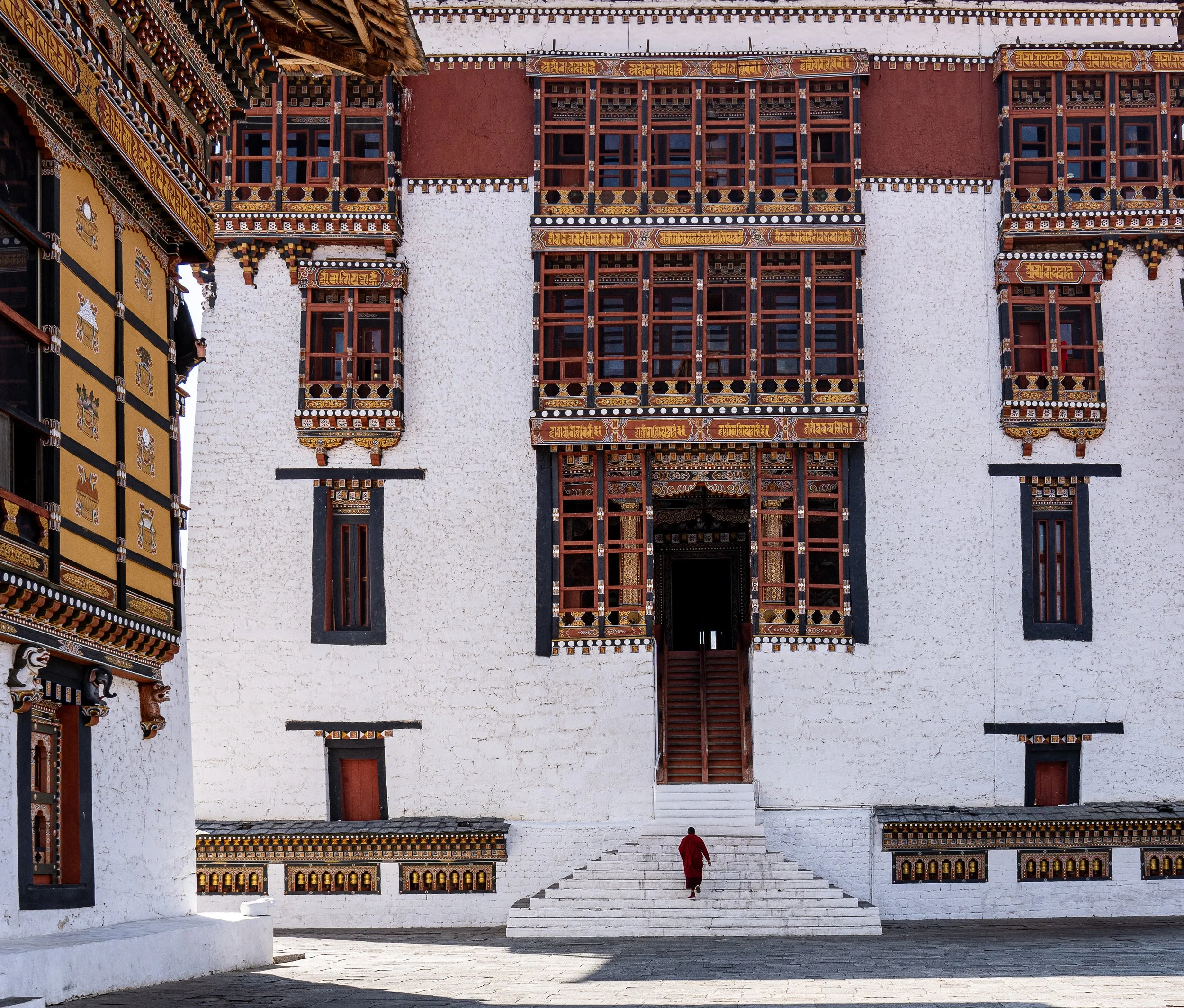 A monk walks up the stares of a Dzong in Bhutan