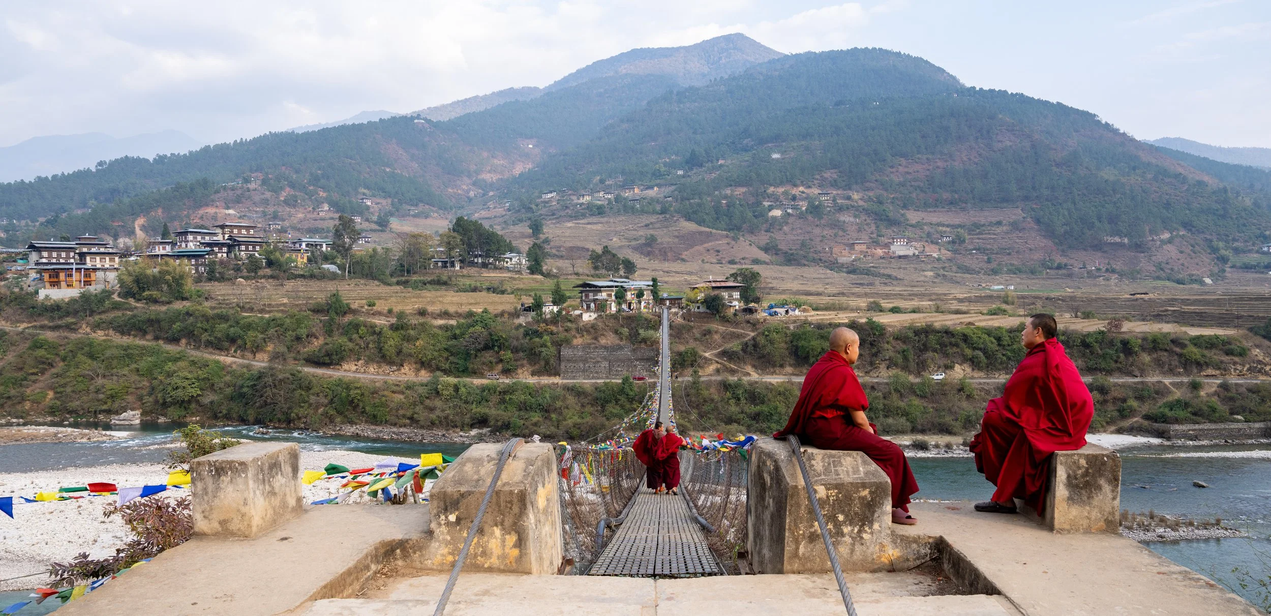 Monks sit at the top of a bridge in Bhutan