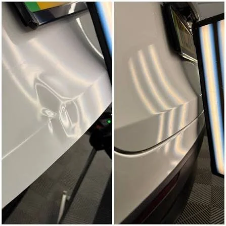 Close-up of a shiny, reflective surface on a white appliance or vehicle, with a monitor and standing object nearby.