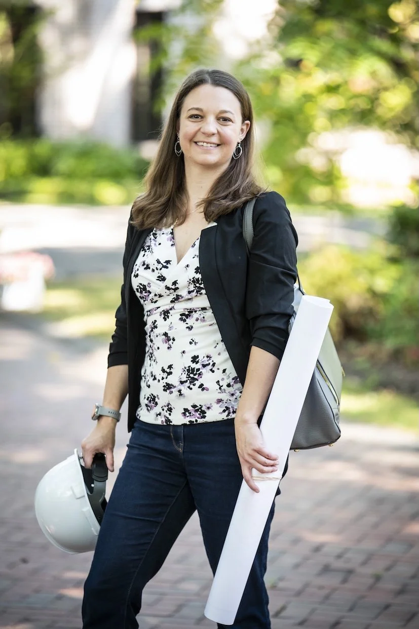 Picture of Katelyn holding a hard hat and a roll of drawings