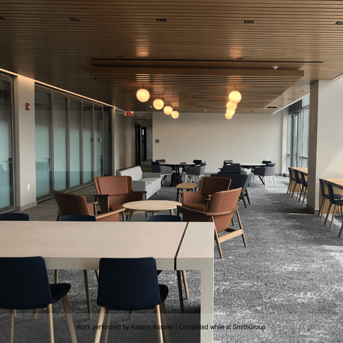 Modern commercial co-working space featuring wooden hot-desking tables and comfortable chairs